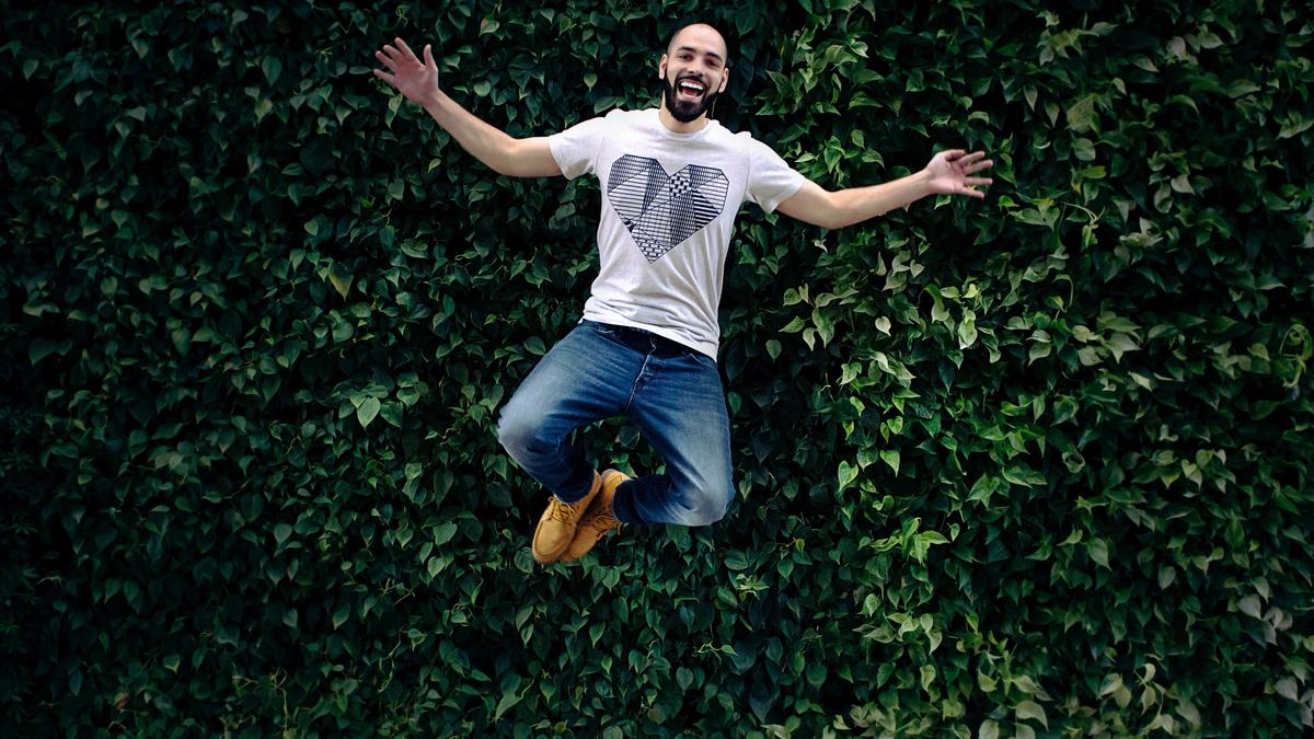Illustrasjonsbilde av en glad mann som hopper med planter i bakgrunnen, tatt av Jonathan Sebastiao fra Unsplash