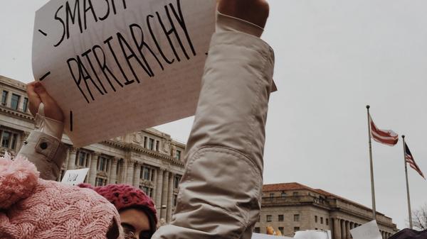 Jente som holder en plakat med ordene: Smash the patriarchy