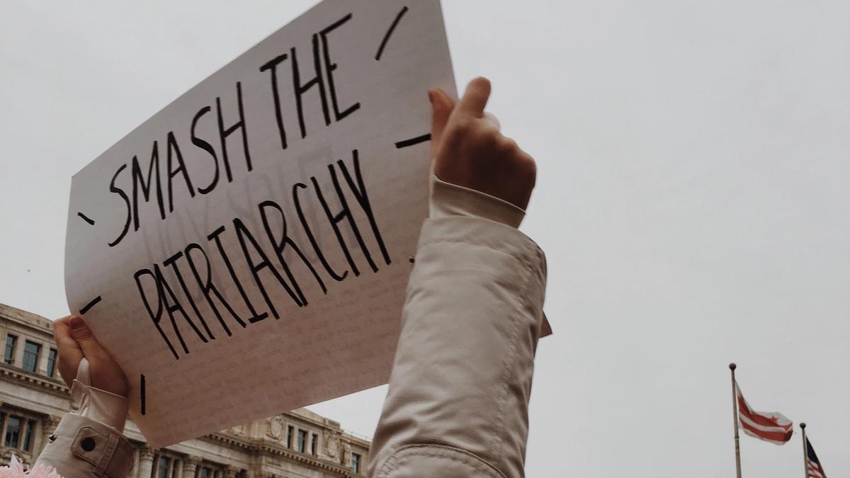 Jente som holder en plakat med ordene: Smash the patriarchy