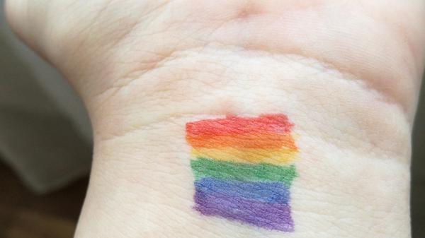 hånd med LGBTQ+ flagget på. Illustrasjonsbilde tatt av chris_photography fra Unsplash