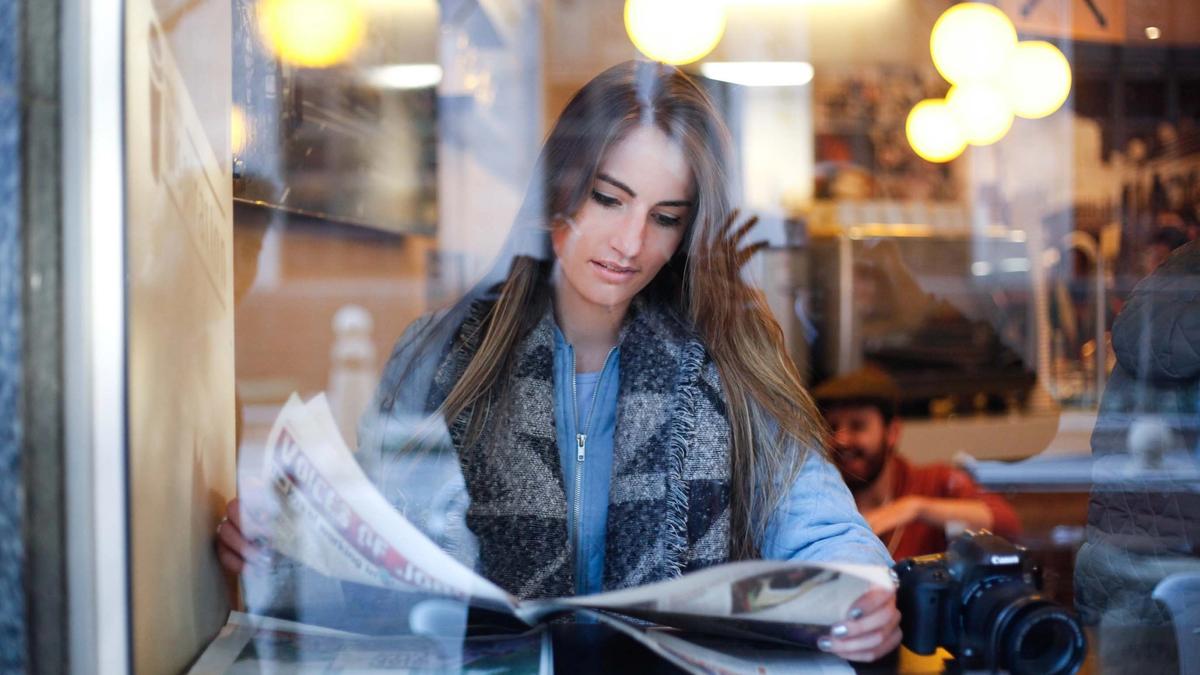Kvinne leser avisen på en kafé