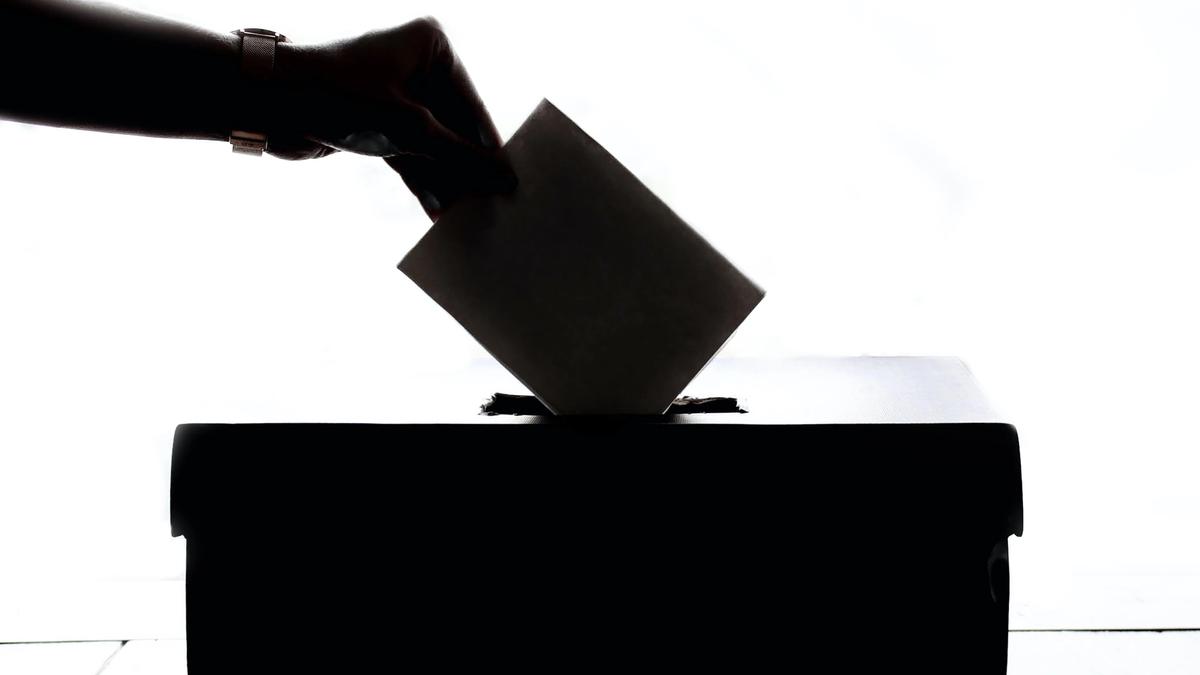 Illustrasjonsbilde som viser en hånd som legger en stemmeseddel i en boks. Bildet er svart hvitt .Tatt av Element5 Digital fra Unsplash