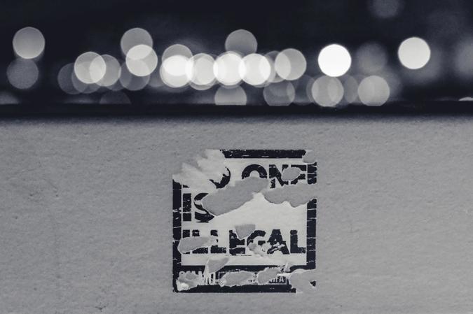 Illustrasjonsbilde av et "No one is illegal" sticker tatt av Ev på Unsplash