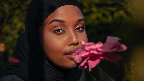 Kvinne som lukter på en rosa blomst