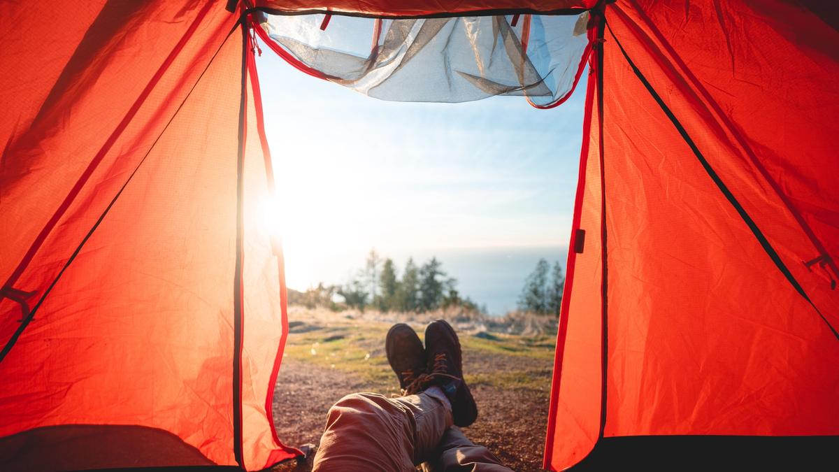 Bilde av et rødt telt med en person som ligger å ser på utsikt i skogen. Illustrasjonsbilde tatt av Will Truettner fra Unsplash