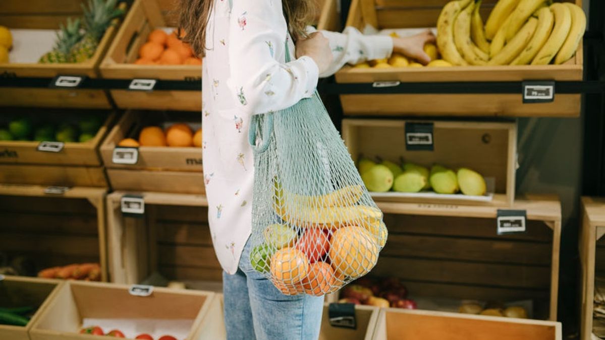 Bilde av en kvinne på en zero waste matbutikk med frukt i et plastfritt handlenett