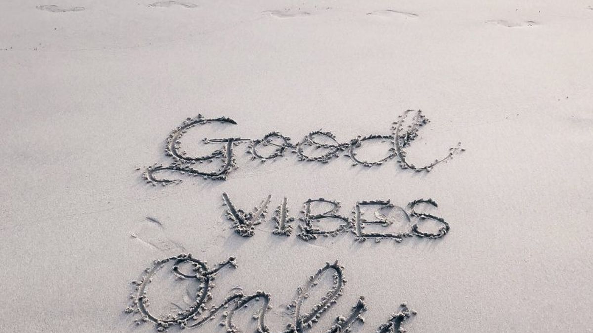 "good vibes only" written in the sand at a beach
