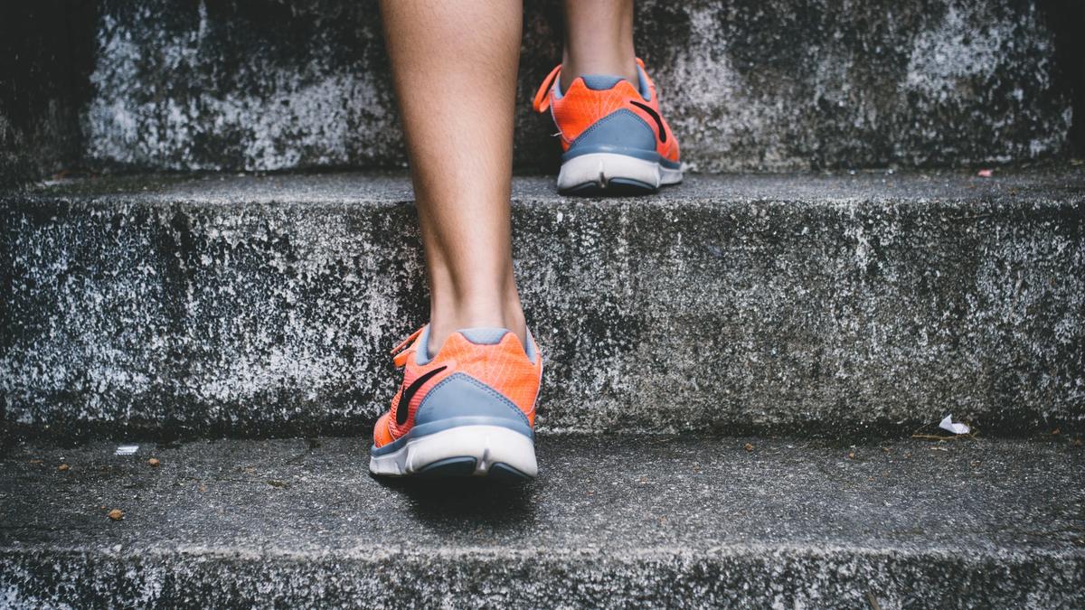Illustrasjonsbilde av en person som går opp ei trapp med orange og grå joggesko tatt av Bruno Nascimento fra Unsplash