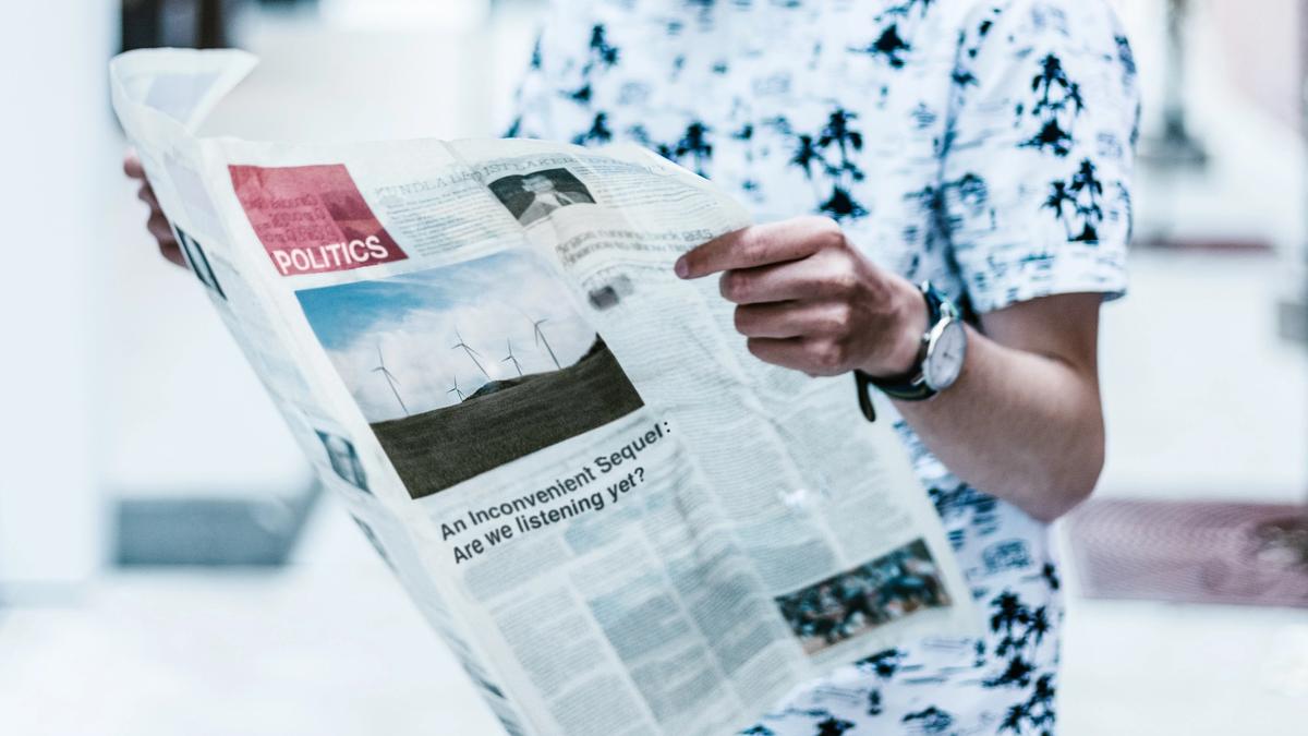 Illustrasjonsbilde av mann i hvit t-skjorte som holder en avis, tatt av Priscilla Du Preez fra Unsplash