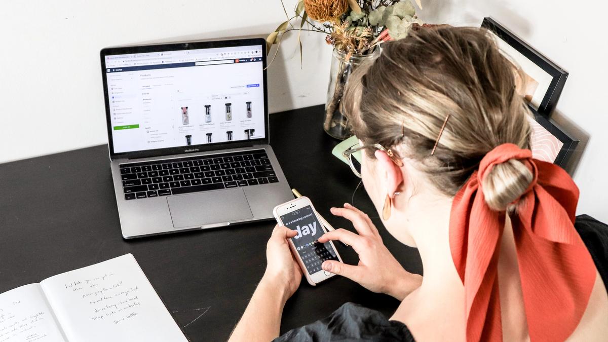en kvinne sitter på pc og mobil