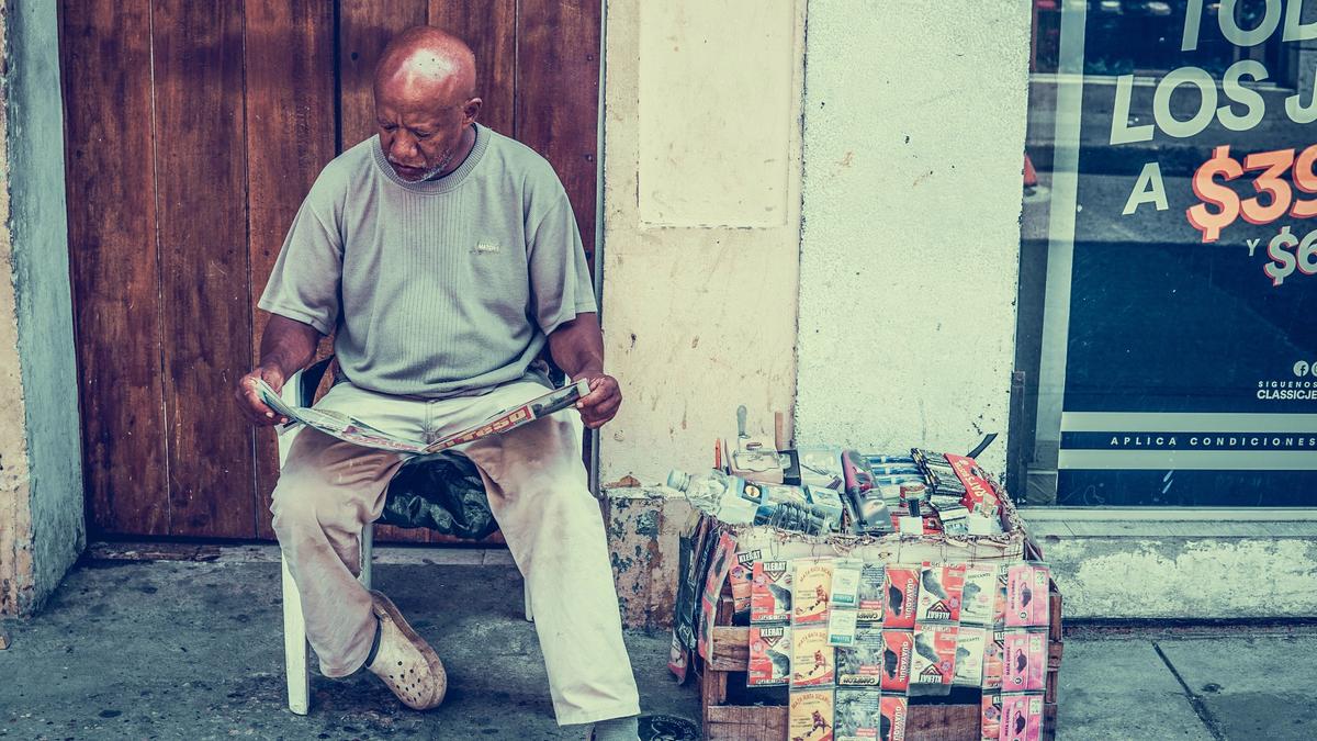 Eldre mann sitter på en stol å leser avisen. Illustrasjonsbilde tatt av Jorge Gardner fra Unsplash