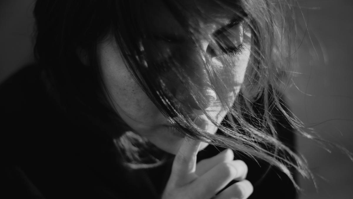 Illustrasjonsbilde i svart hvit farge av en kvinne med langt hår som faller foran ansiktet tatt av Gabriel Benois fra Unsplash