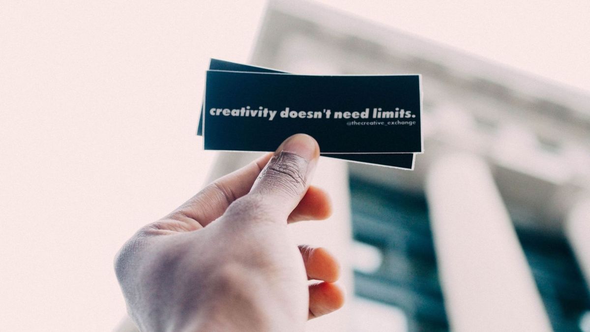 Illustrasjonsbilde av en hånd som holder opp en svart lapp hvor det står skrevet i hvitt : "creativity doesn´t need limits"