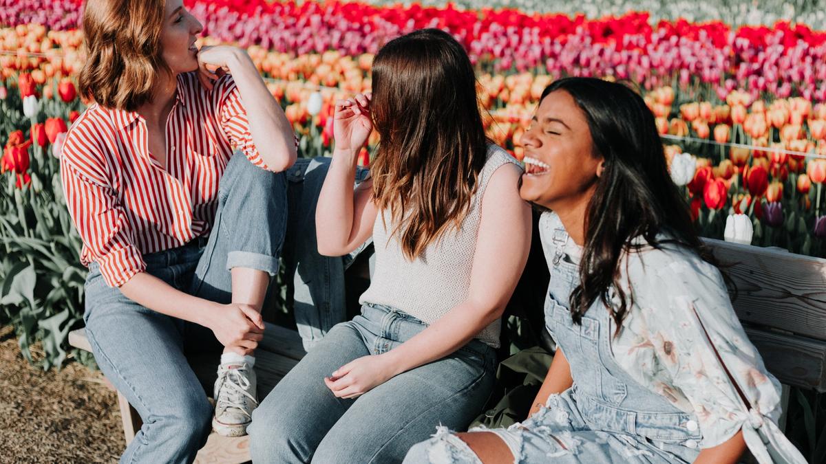 Tre kvinner som sitter på en benk med tulipaner i bakgrunnen. Illustrasjonsbilde tatt av Priscilla Du Preez fra Unsplash