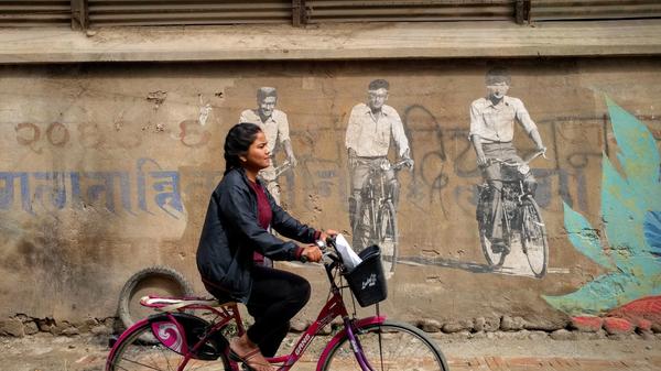 En nepalsk jenter sykler i en gate 