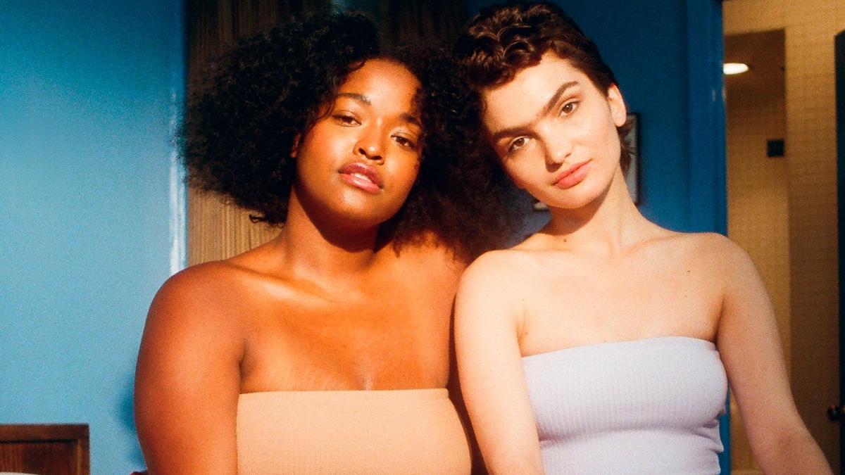 To vakre kvinner som sitter i en seng