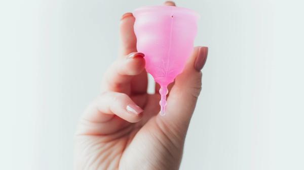 En hånd som holder en rosa menskopp
