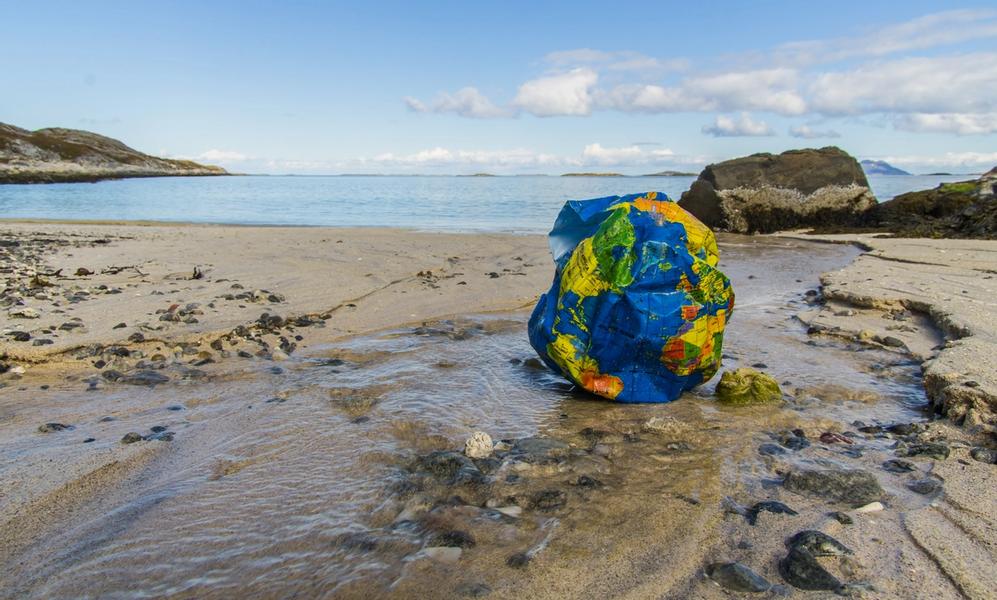 Badeball i plast med verdenskart på strand i Nord Norge