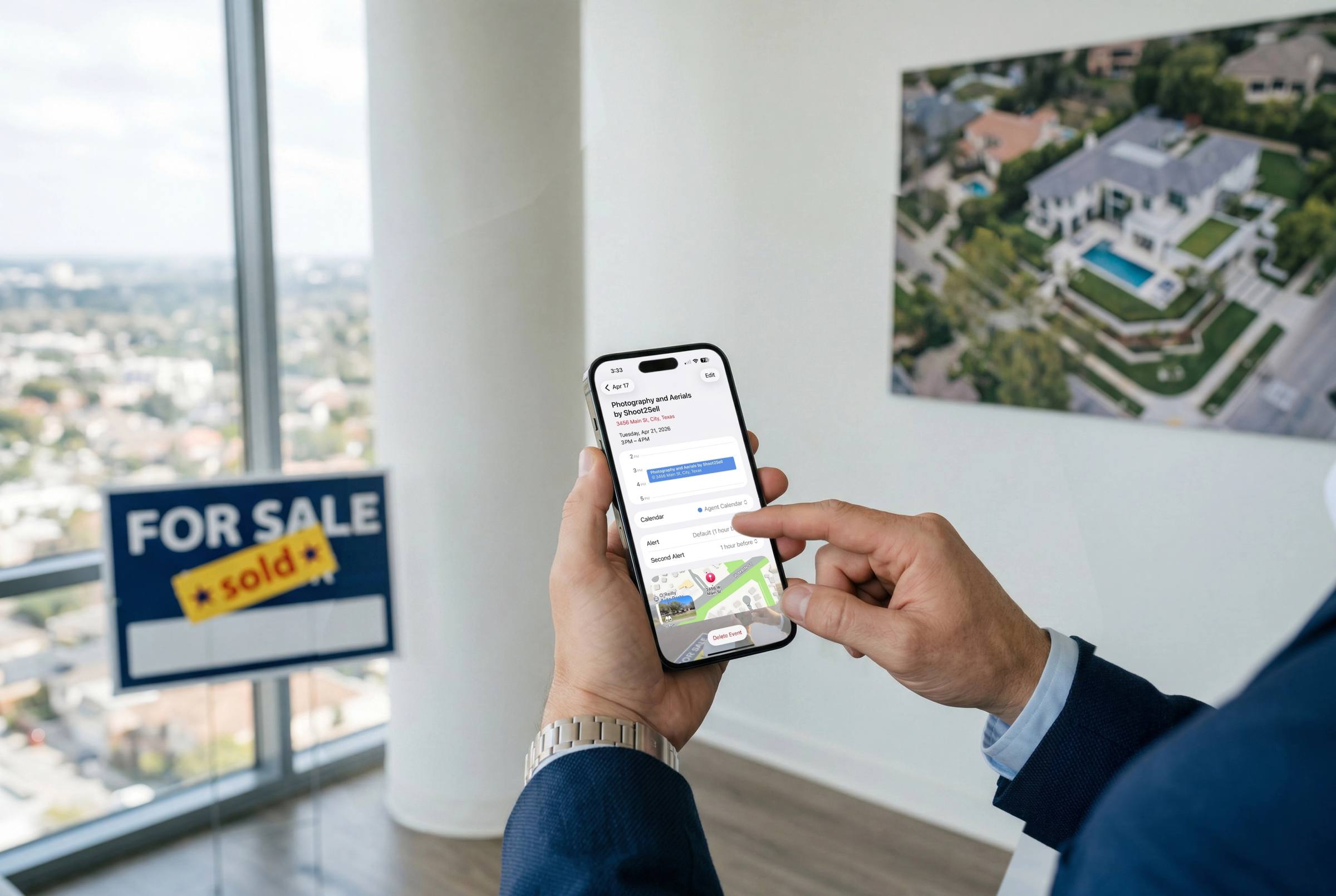 Real estate agent browsing property listings on smartphone with For Sale Sold sign and aerial photo in a Texas office
