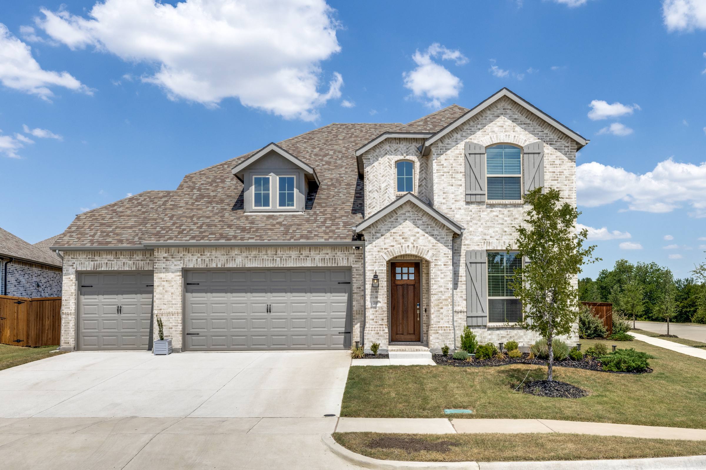Two-story brick home in Melissa with sparse, patchy front lawn before green grass photo enhancement