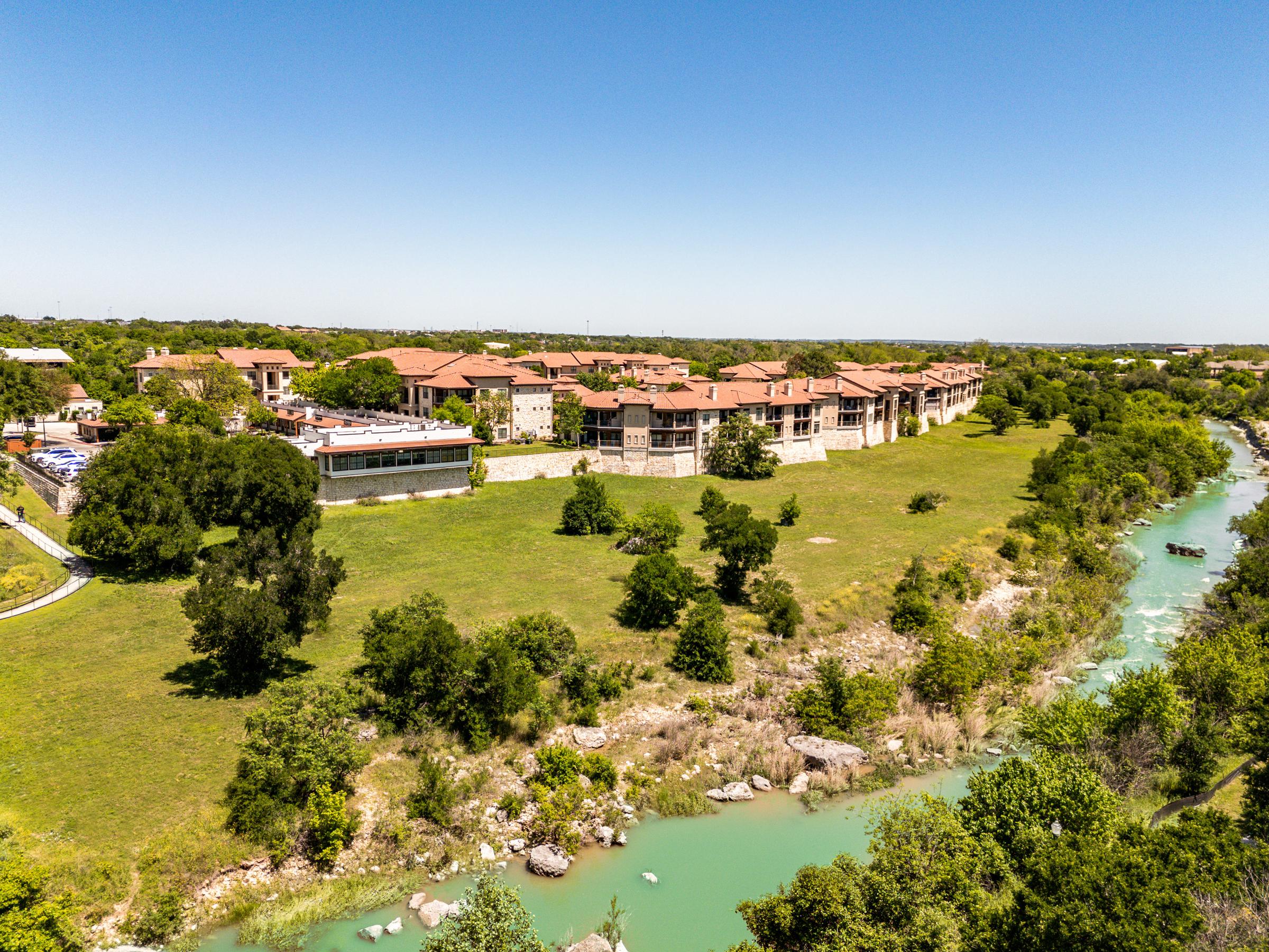 Aerial view of a Tuscan-style riverside condominium community beside the San Gabriel River in Georgetown