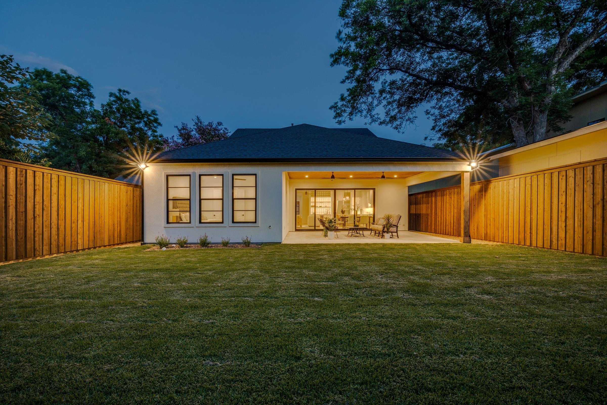 Modern white stucco home with covered patio and manicured lawn at twilight in Dallas, Texas