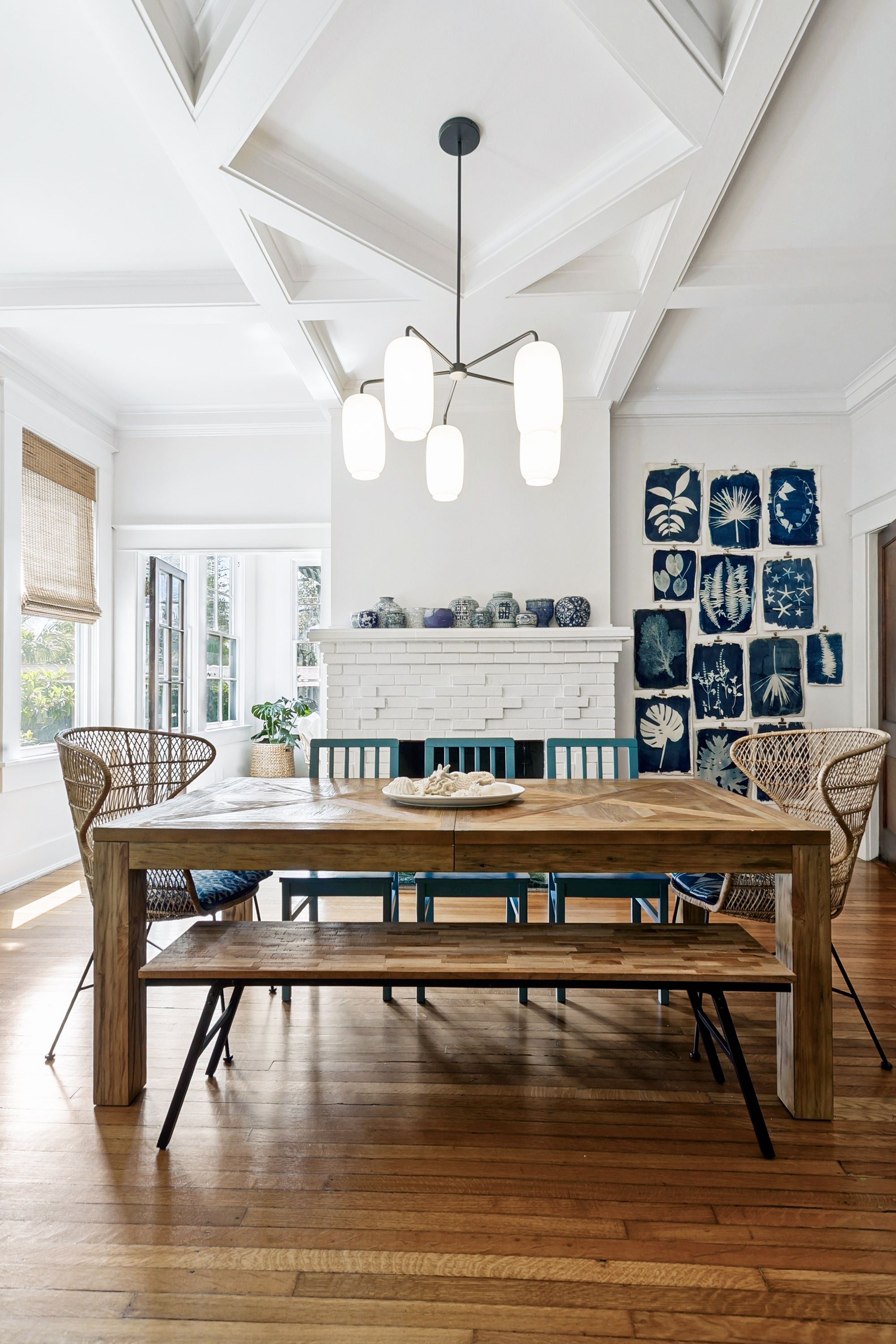 Elegant dining room with coffered vaulted ceiling, rustic wood table, and gallery wall of botanical prints in San Antonio, Texas