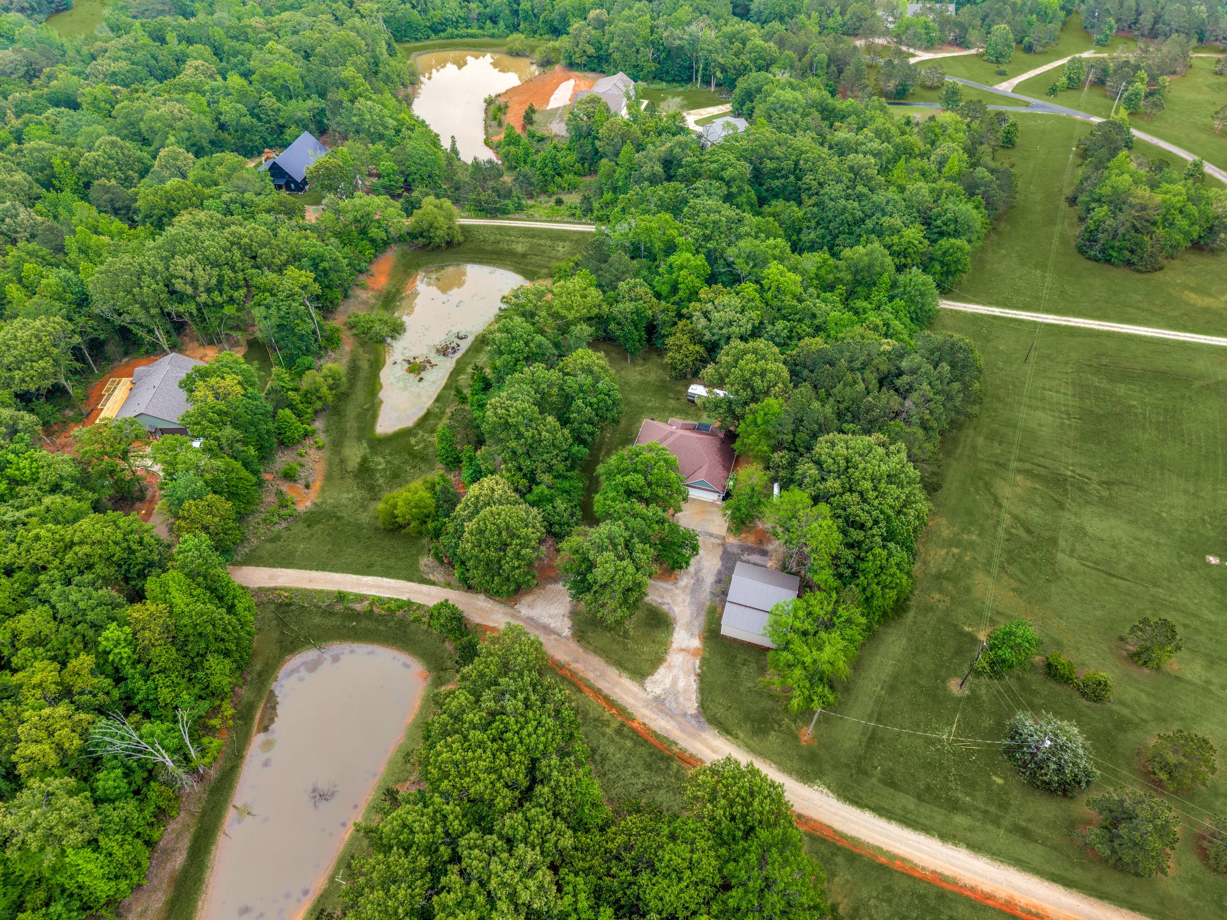 Aerial view of a rural Thedford, TX estate with main house, outbuildings, and multiple stock ponds — grass vibrantly greened by Shoot2Sell's Aerial Green Grass enhancement.