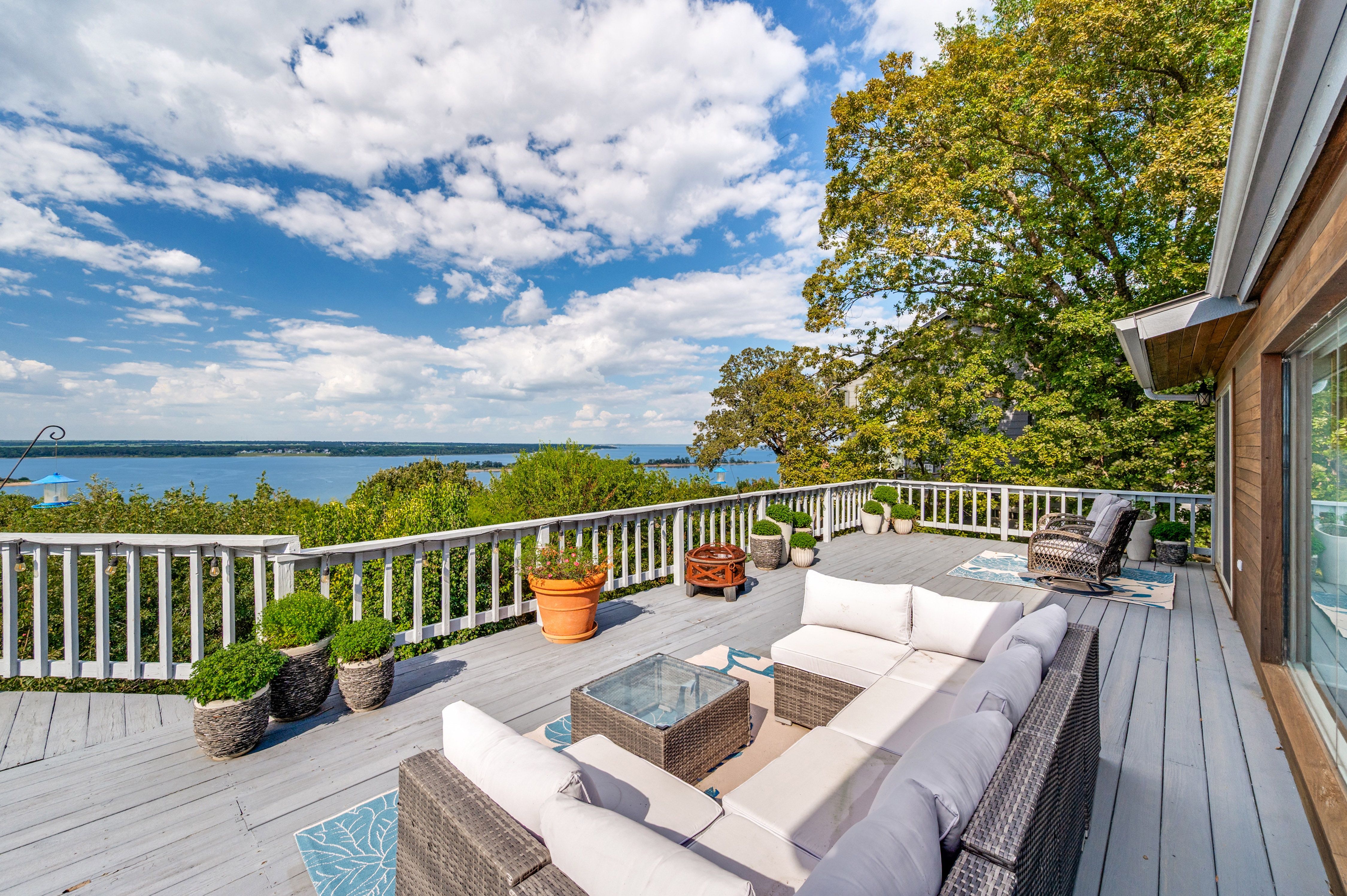 Spacious outdoor deck with wicker furniture and panoramic Lake Texoma views under blue skies in Pottsboro, Texas