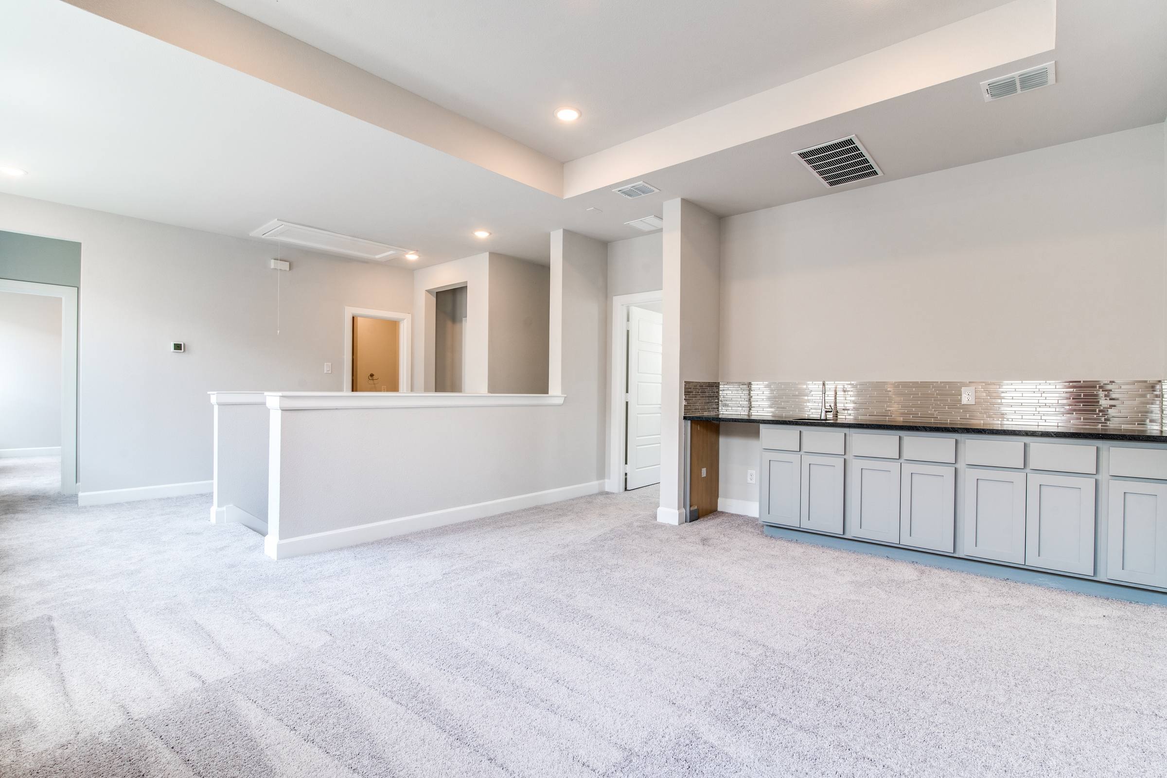 Empty game room with wet bar and half wall before virtual staging in new build home in Heath, Texas