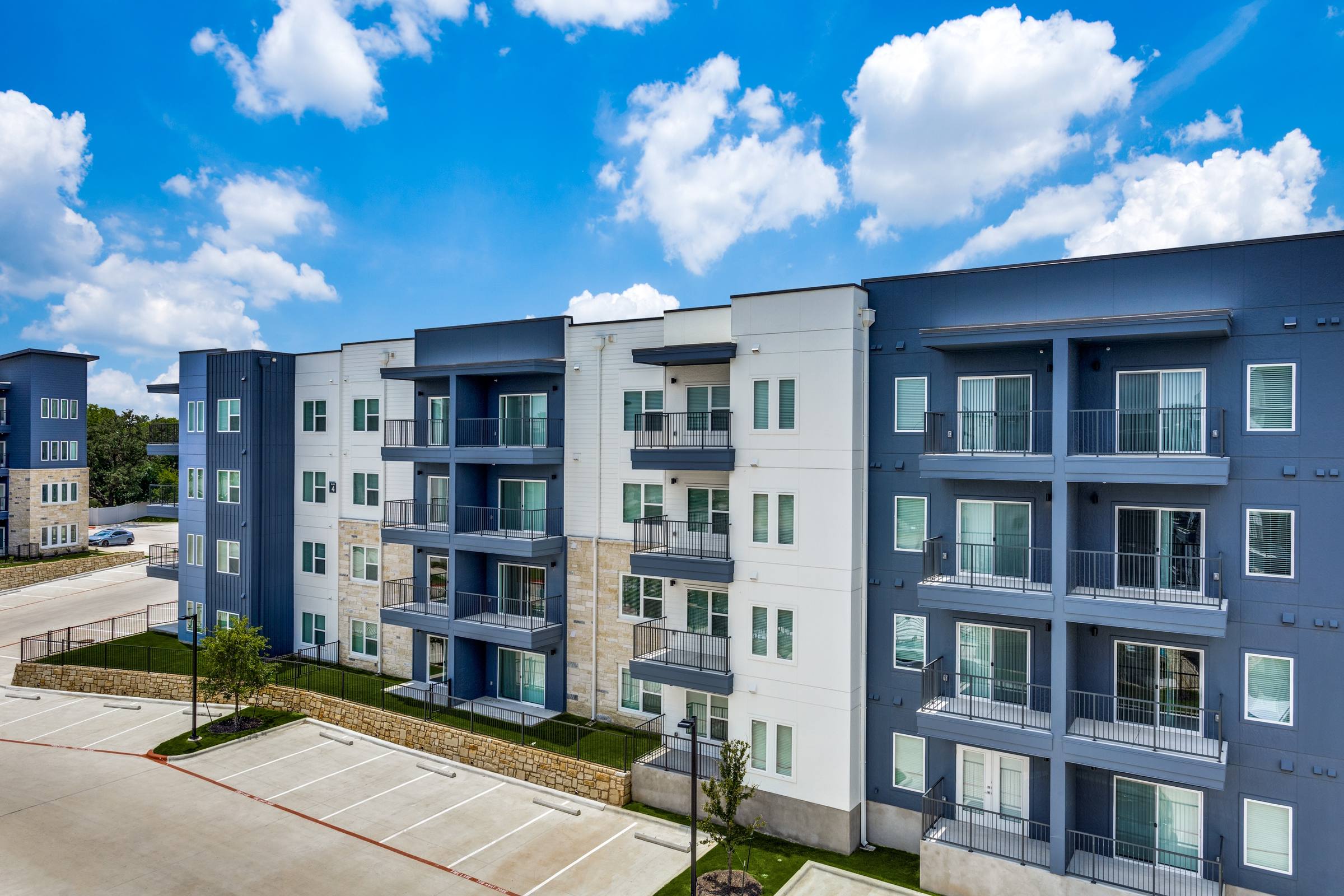 Aerial drone view of a modern multi-story apartment building with balconies and stone accents in Austin, Texas