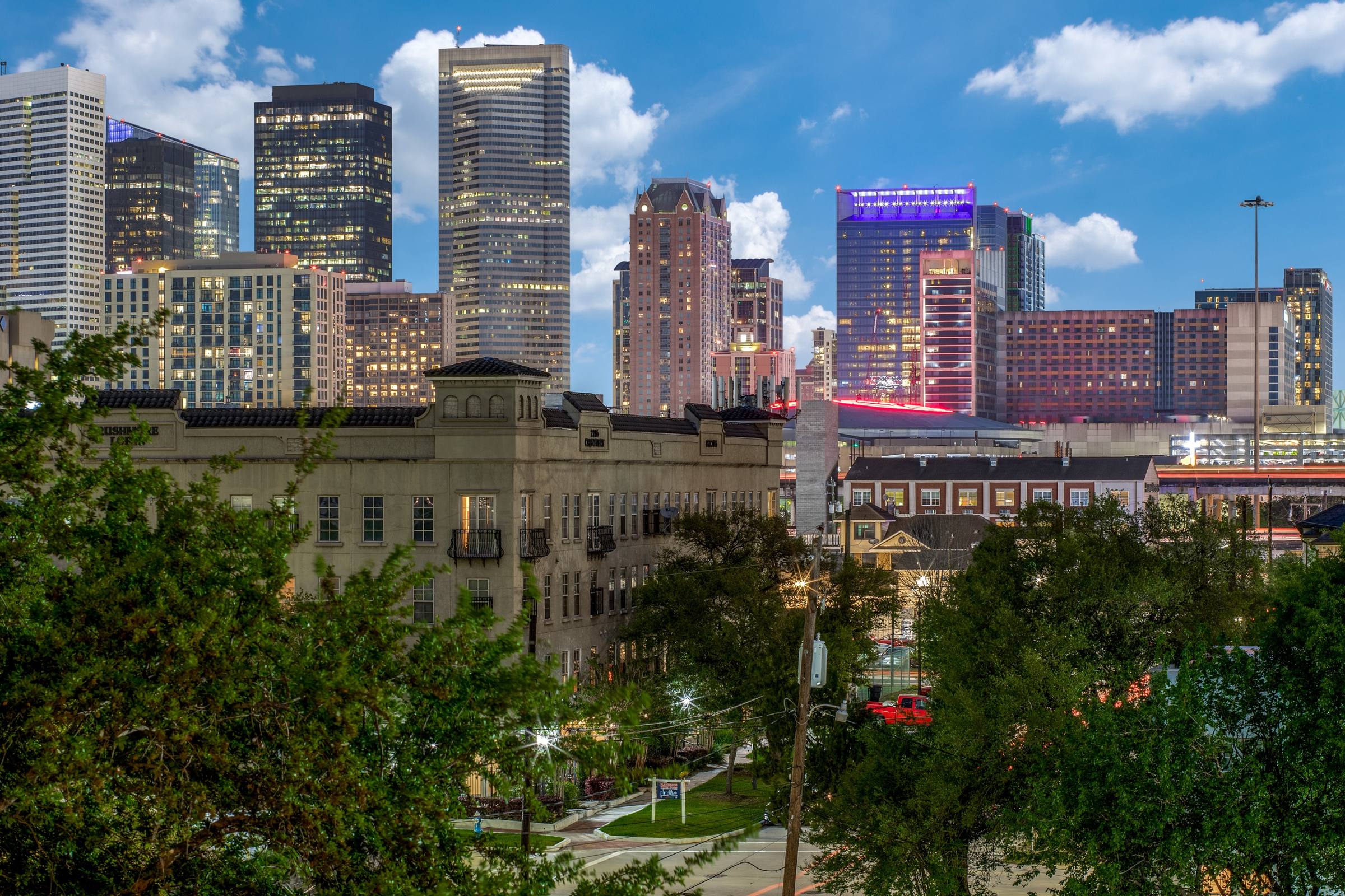 Houston downtown skyline at dusk with illuminated highrises and historic Midtown buildings in the foreground, Houston, Texas