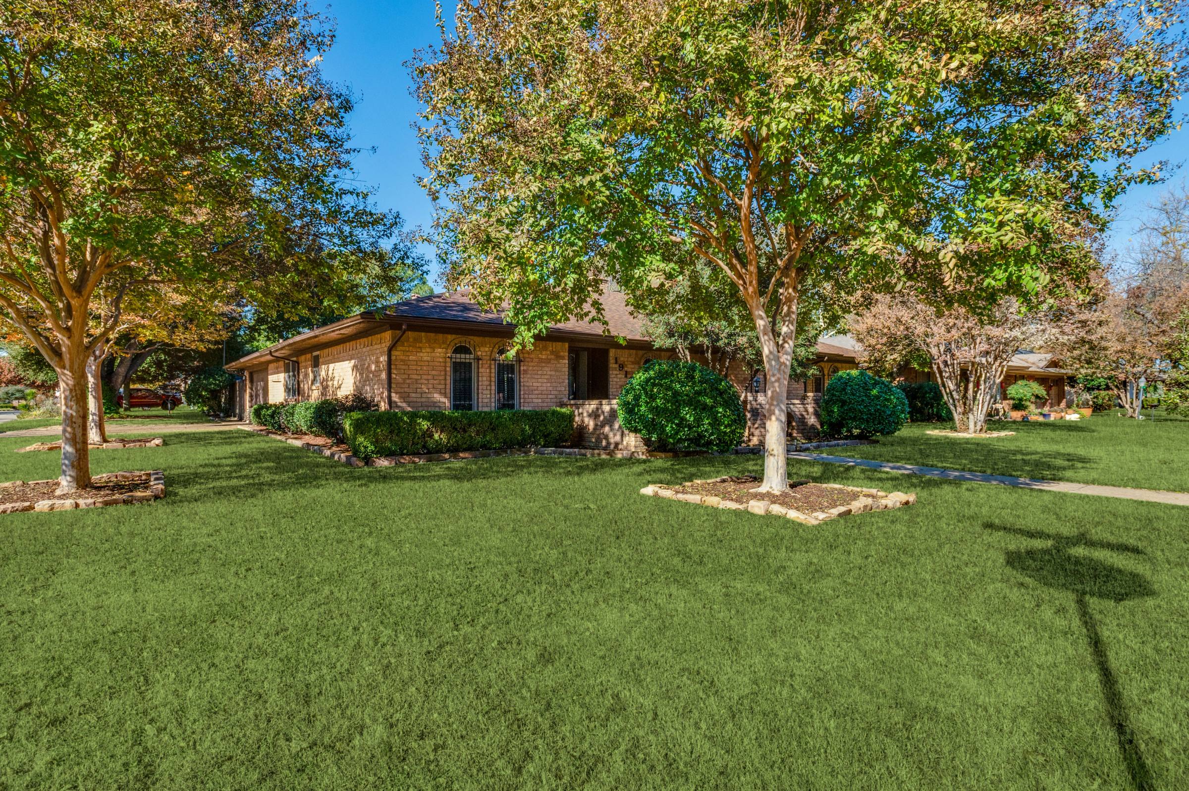 Single-story brick ranch home in Arlington with lush green front lawn after green grass photo enhancement