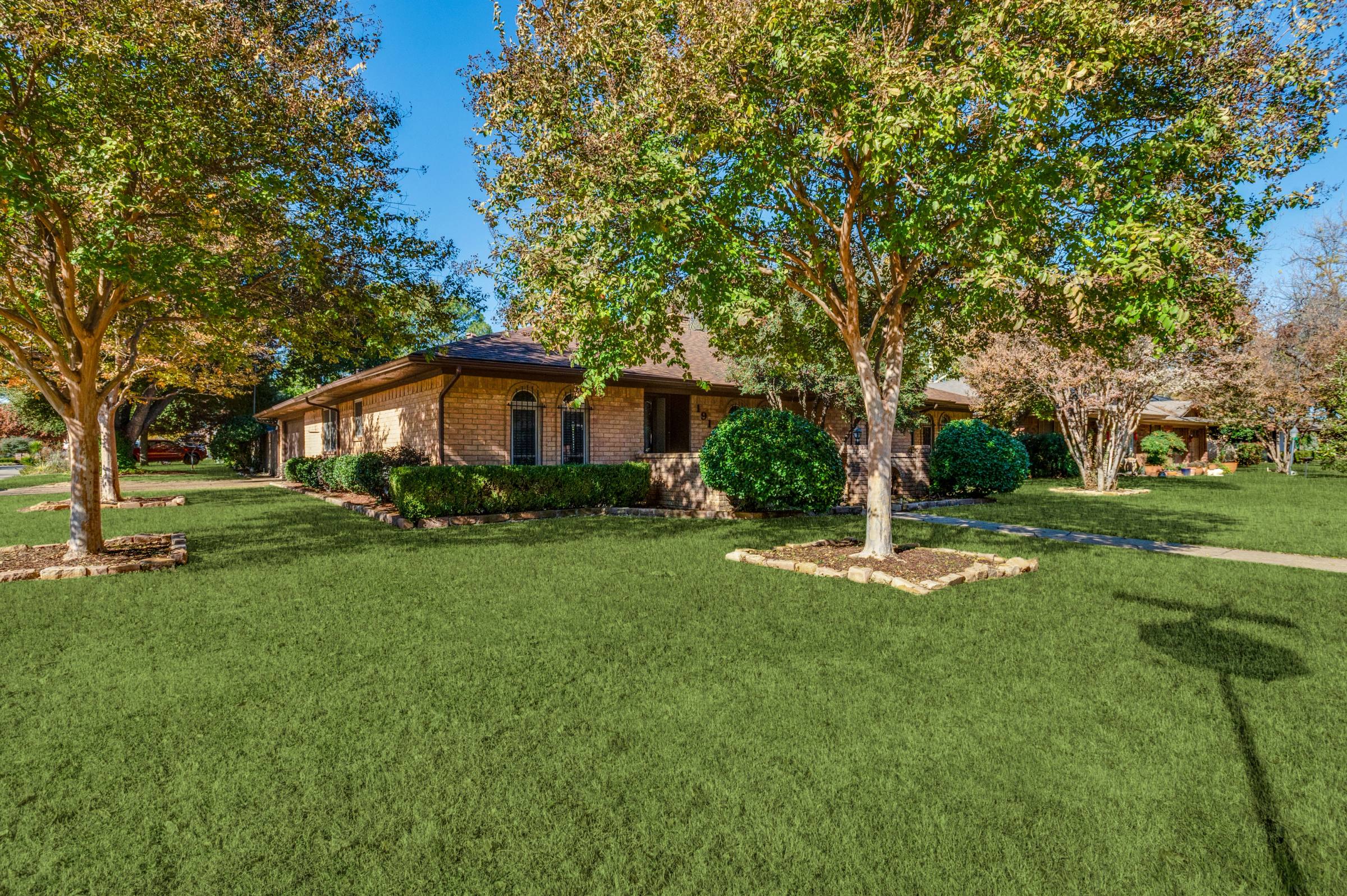 Single-story brick ranch home in Arlington with lush green front lawn after green grass photo enhancement