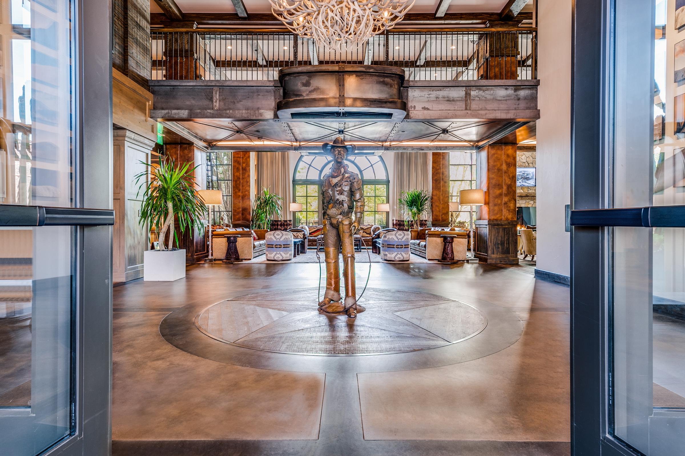 Rustic luxury hotel lobby with antler chandelier, bronze cowboy statue, and Texas star floor medallion in Fort Worth, Texas