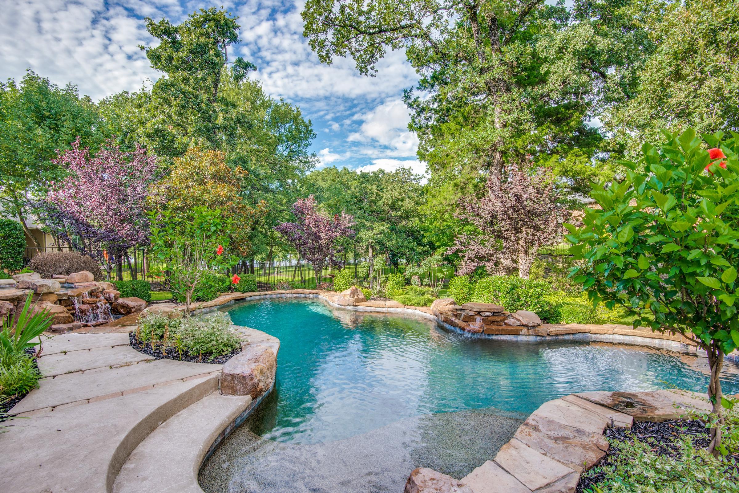 Freeform pool with rock waterfall and lush flowering landscaping in Highland Village, Texas