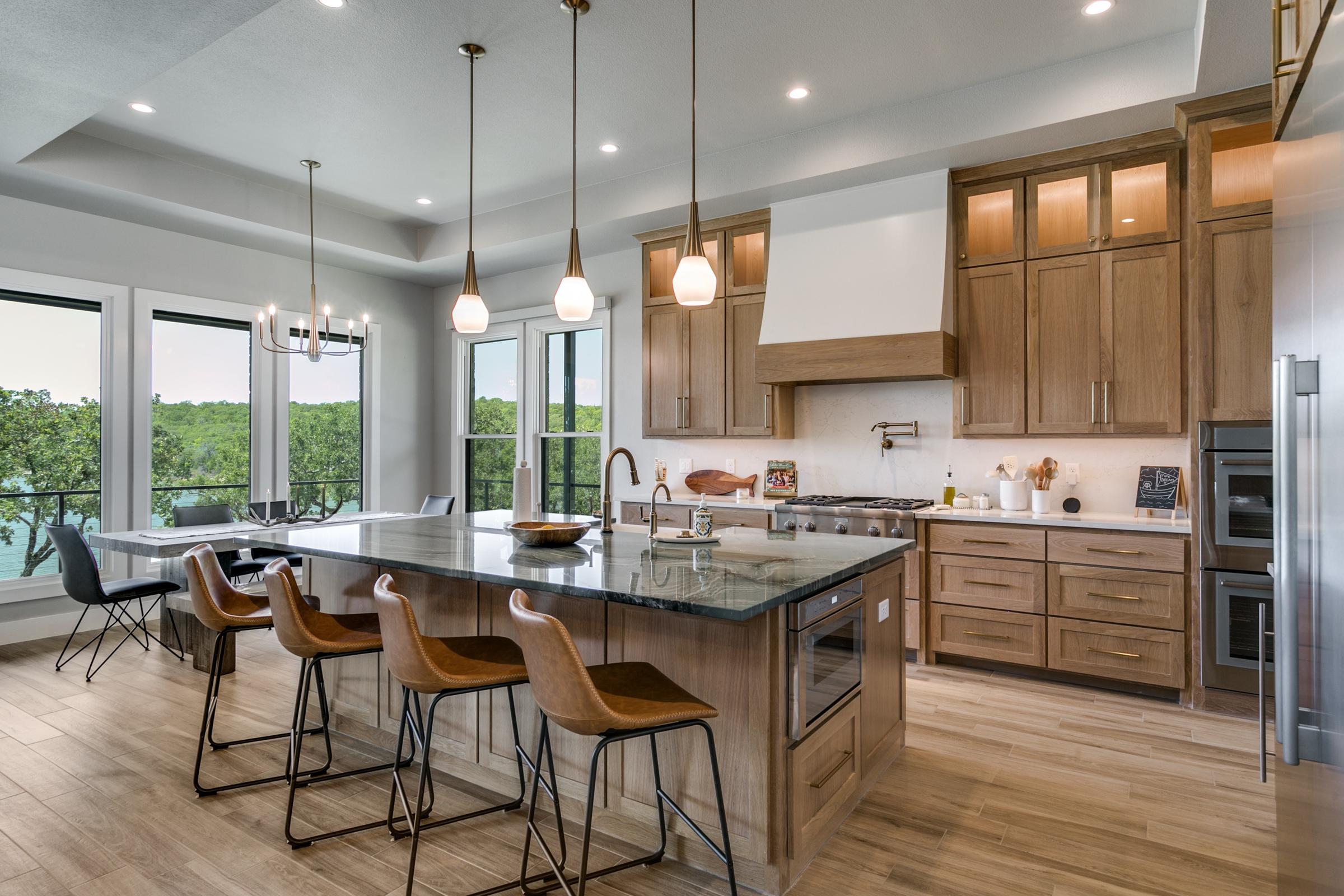 Spacious kitchen with large island, wood cabinetry, pendant lights, and panoramic lake views in Chico, Texas