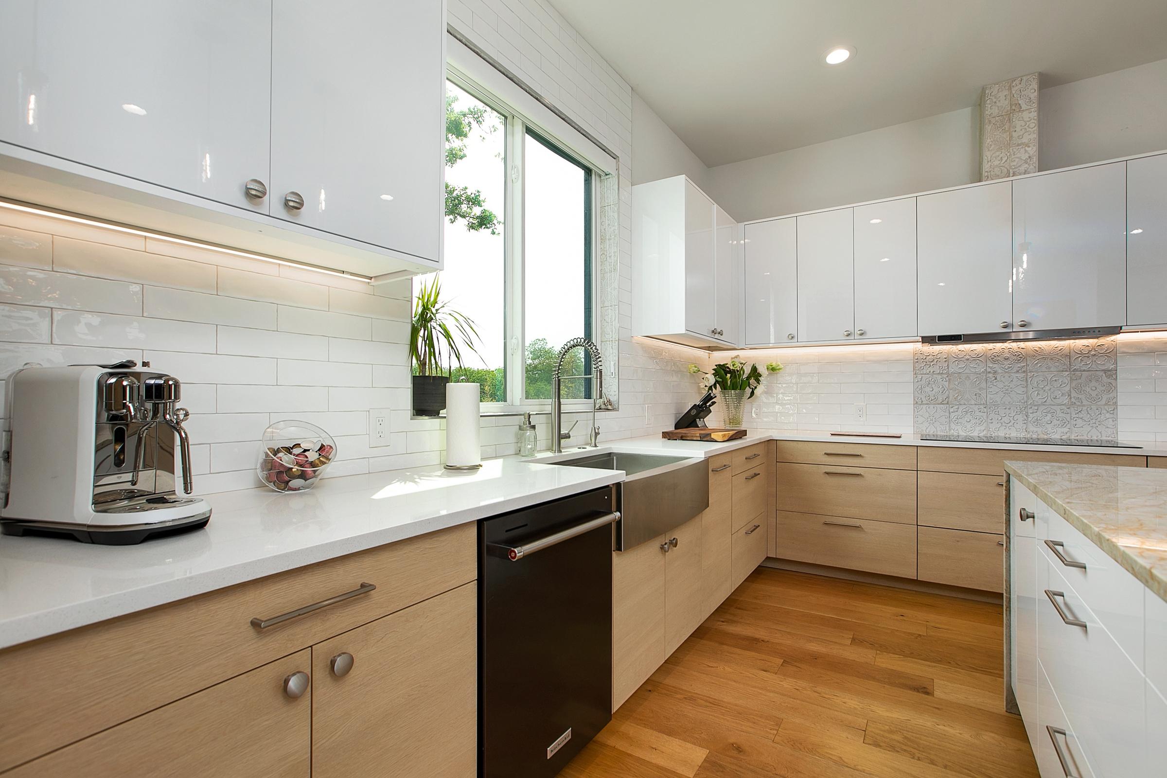 Modern U-shaped kitchen with two-tone cabinetry, quartz countertops, under-cabinet lighting, and garden window in San Antonio, Texas