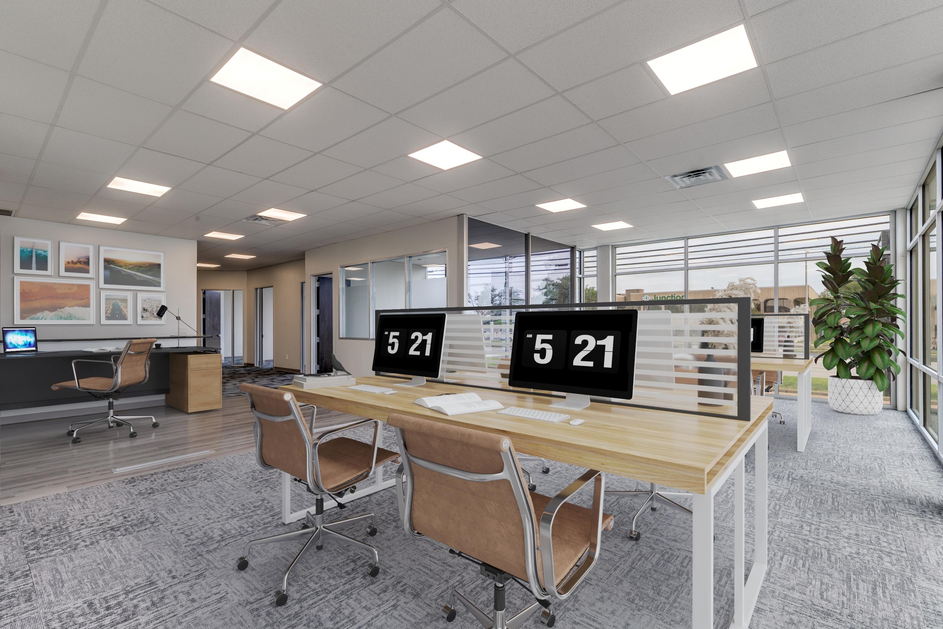 Virtually staged commercial office with desks, monitors, chairs, gallery wall, and plant accents in Farmers Branch, Texas