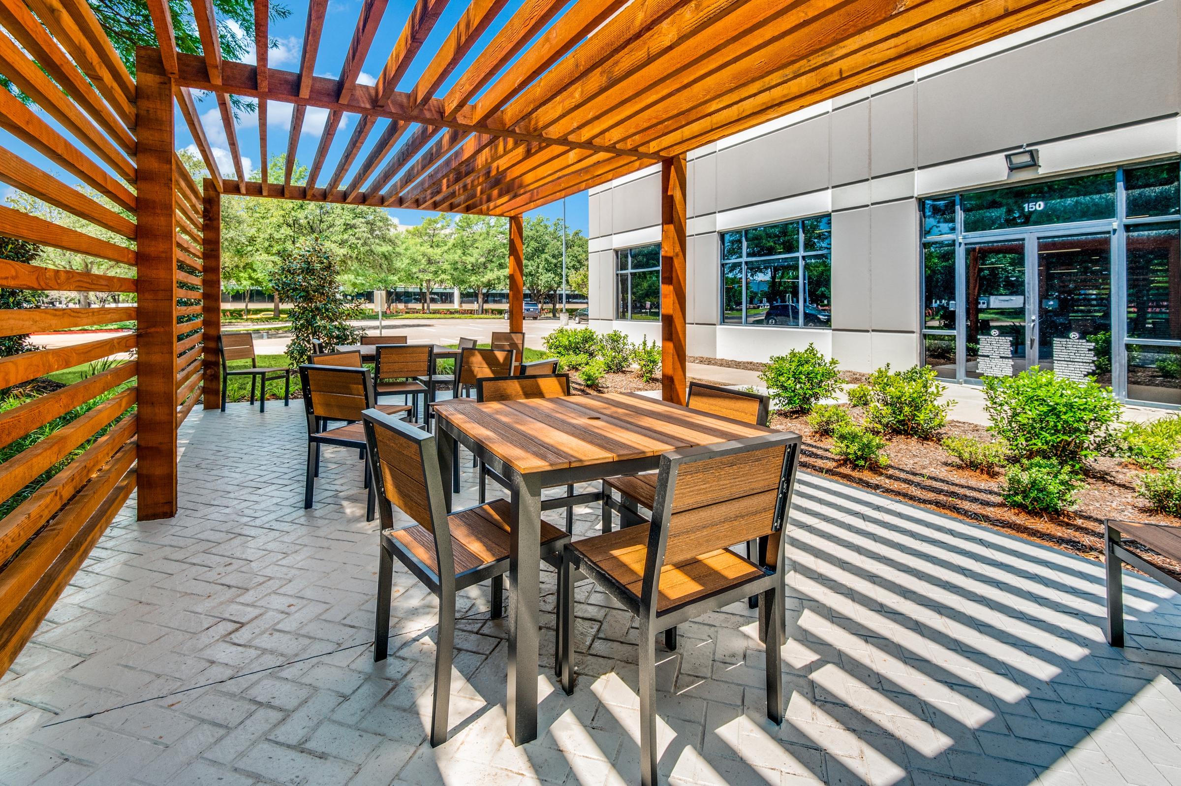 Modern outdoor seating area with wood pergola and patio furniture at a commercial office building in Texas