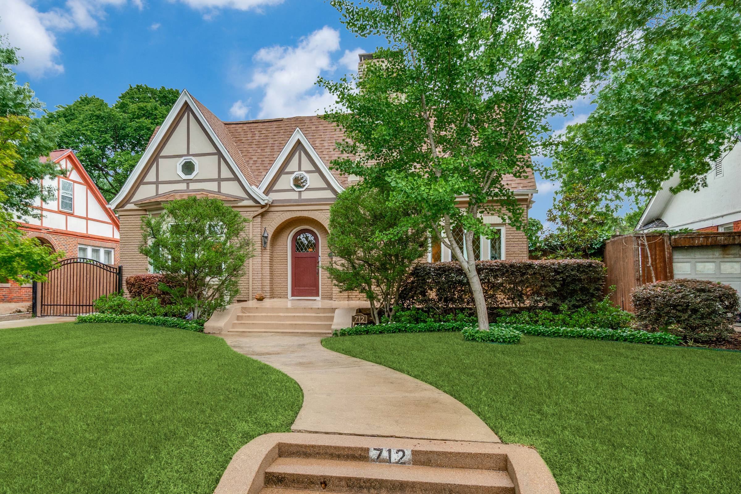 Tudor-style home front exterior in Dallas with vibrant blue sky and white clouds after blue skies photo enhancement