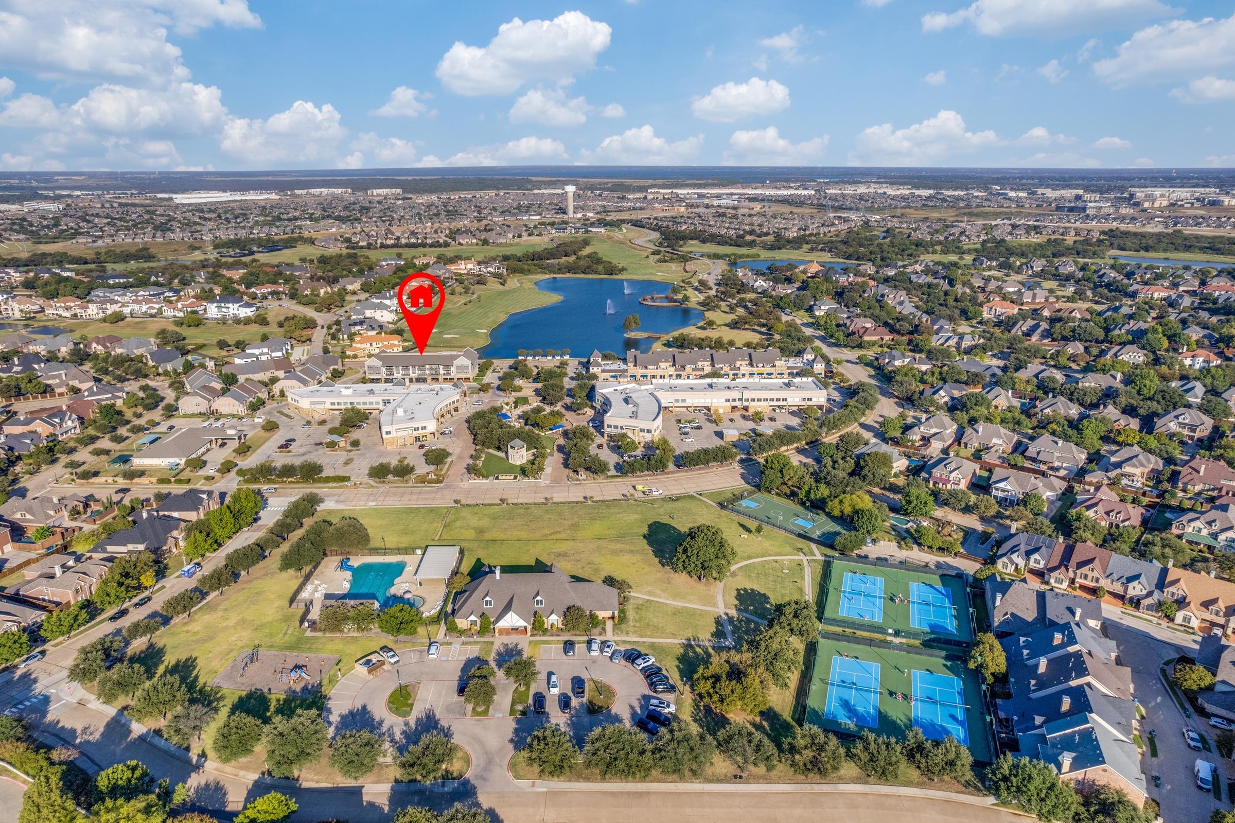 High-altitude aerial view of a master-planned community with lake, tennis courts, pool, and clubhouse in Lewisville, Texas