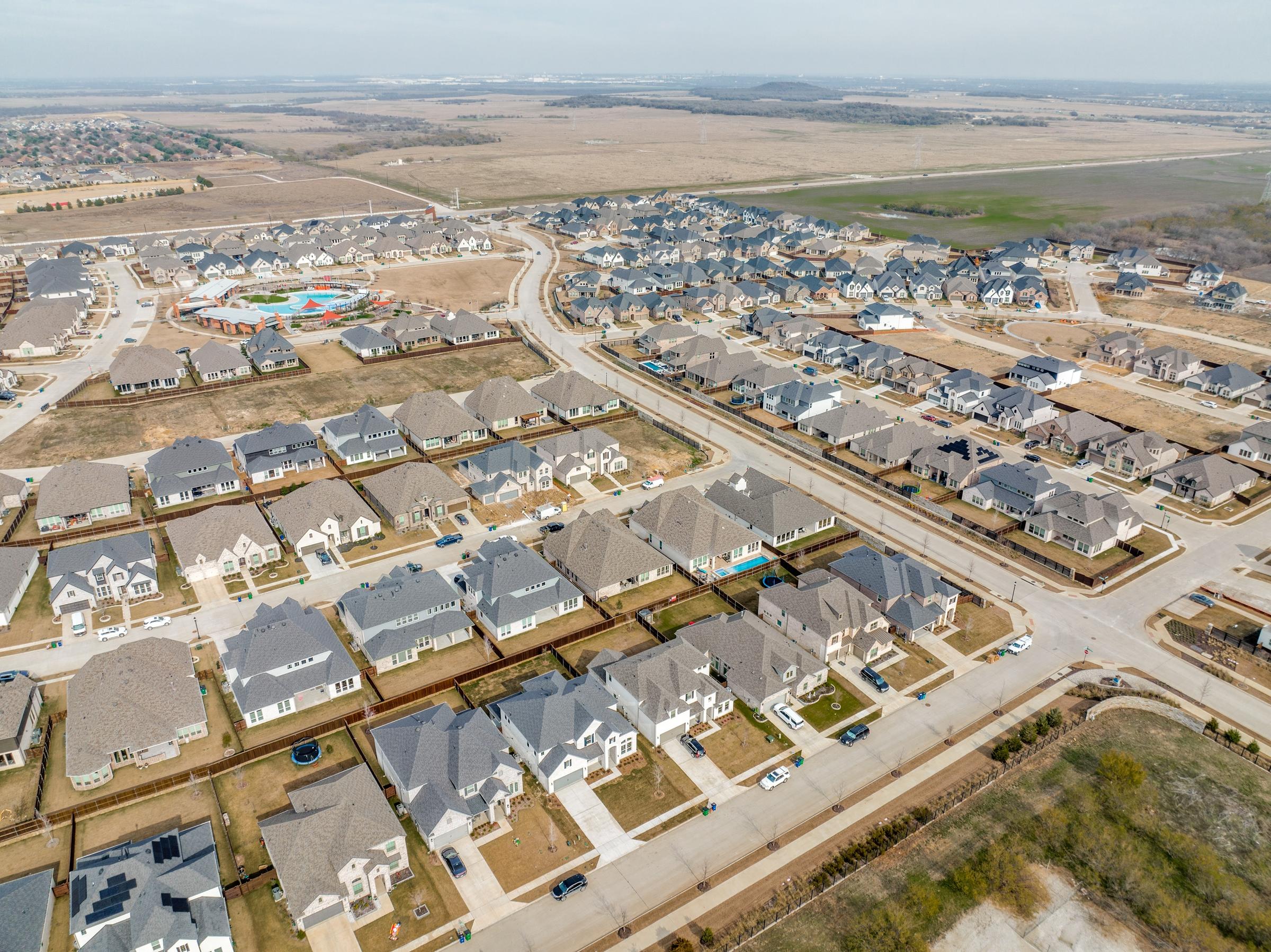 Aerial drone view of a new construction master-planned community with community pool and homes under construction in Northlake, Texas