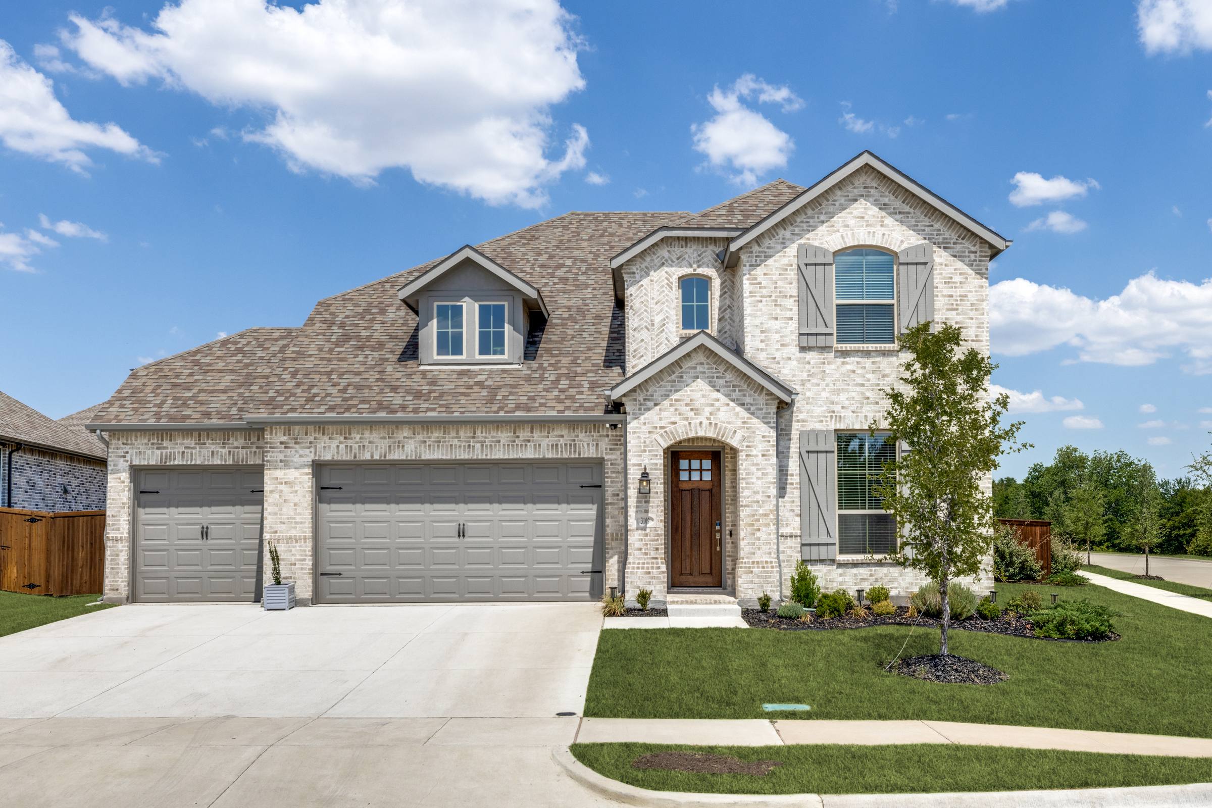 Two-story brick home in Melissa with full lush green front lawn after green grass photo enhancement