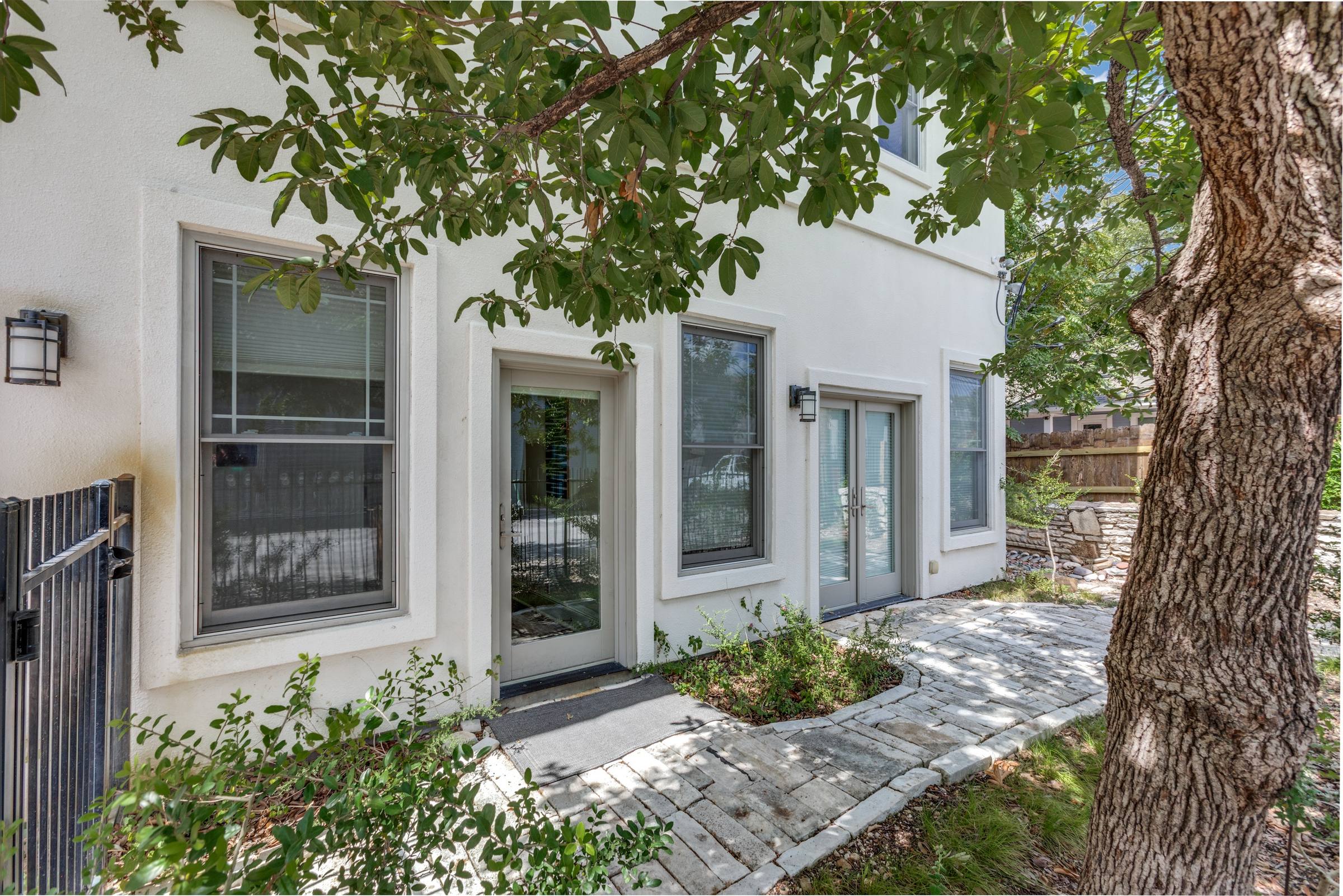 Rental property entrance with stone walkway, mature tree canopy, and white stucco facade in Austin, Texas