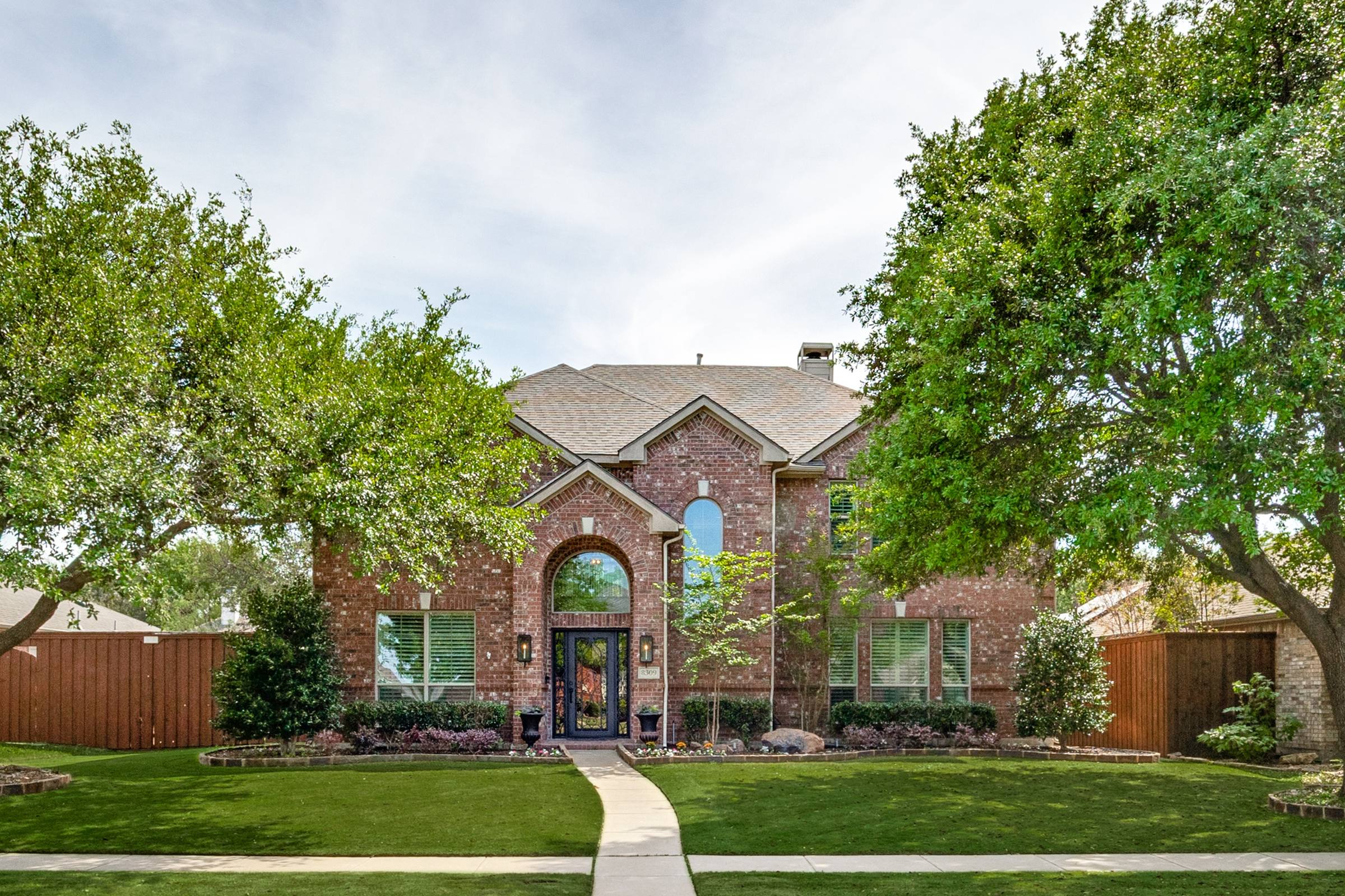 Daytime photo of a two-story brick home with overcast sky before digital twilight enhancement in Frisco, Texas
