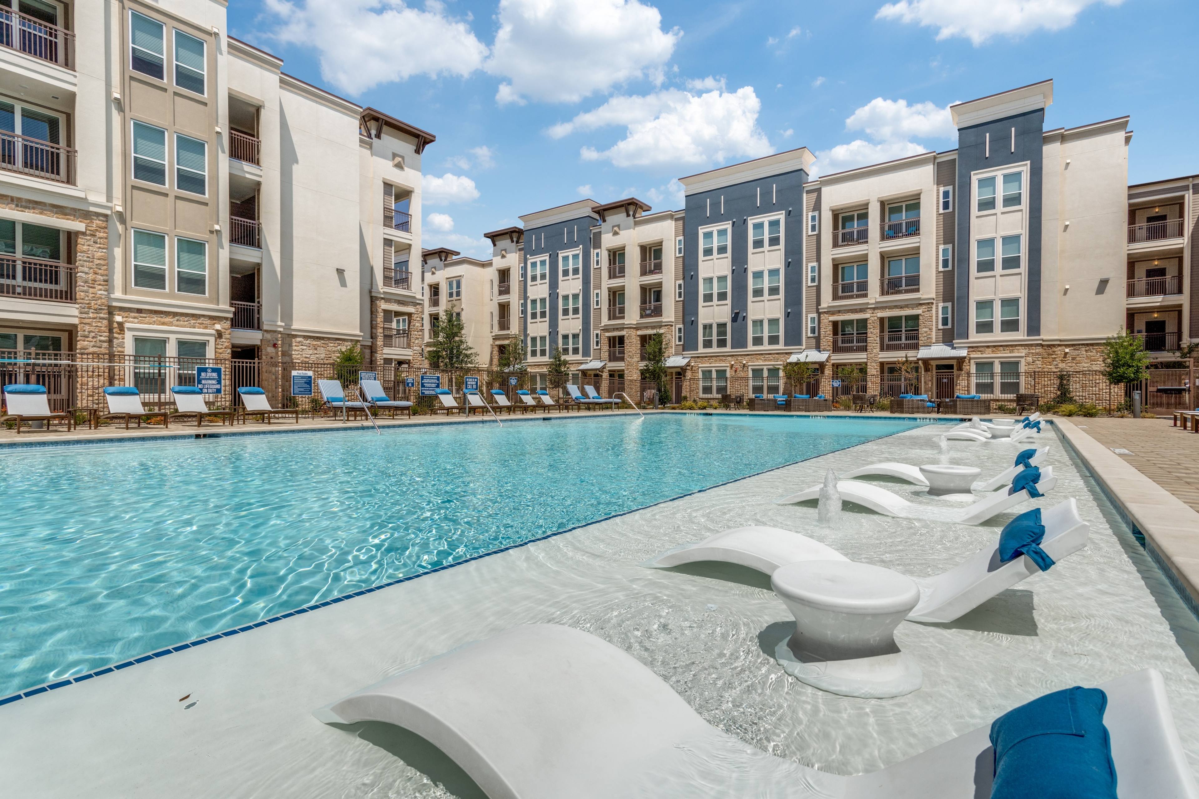Resort-style pool with in-water tanning ledge loungers at a modern apartment community in Allen, Texas