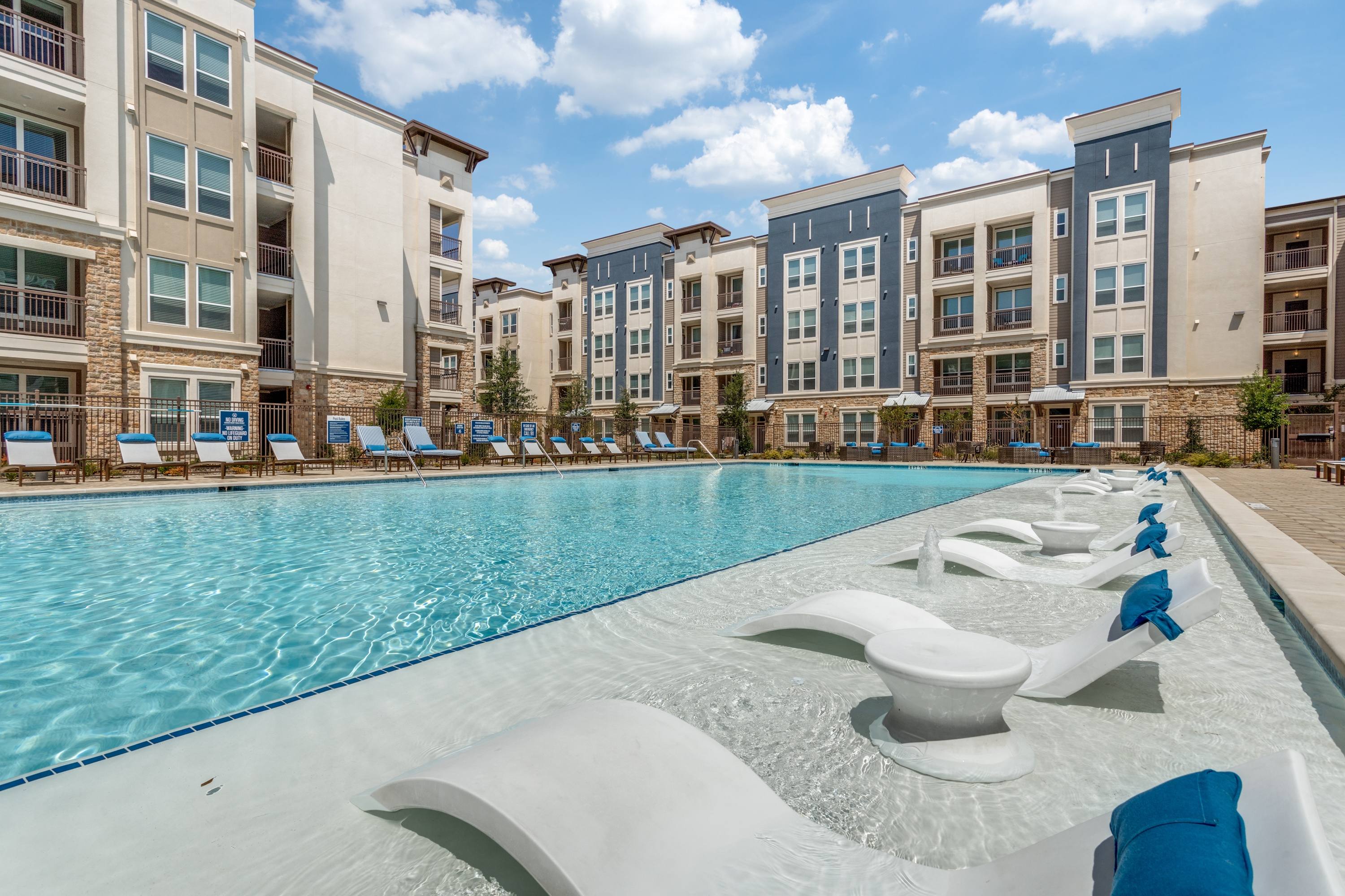 Resort-style pool with in-water tanning ledge loungers at a modern apartment community in Allen, Texas