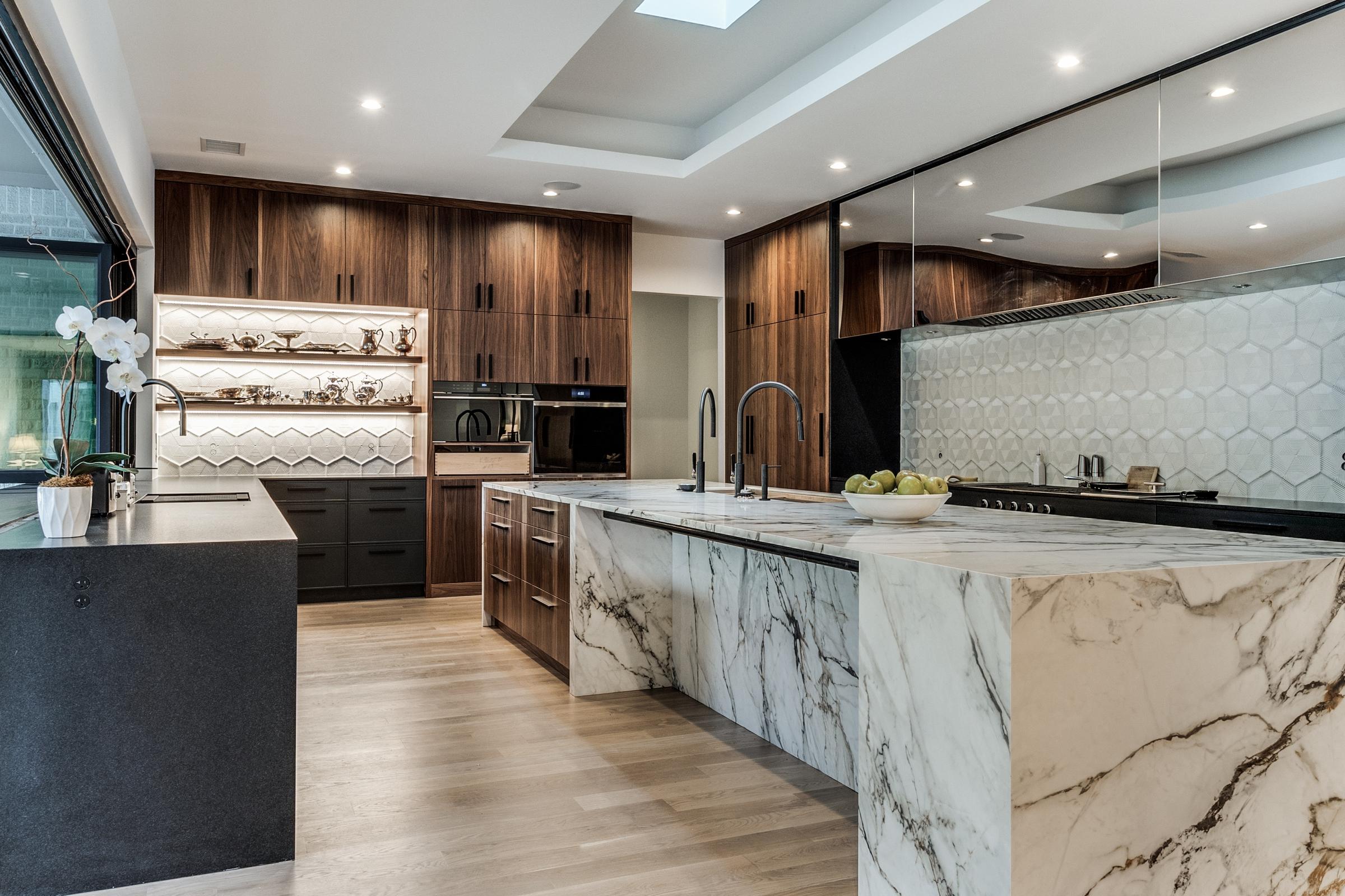 Luxury custom kitchen with calacatta marble waterfall island, walnut cabinetry, hexagonal tile backsplash, and skylight in Dallas, Texas