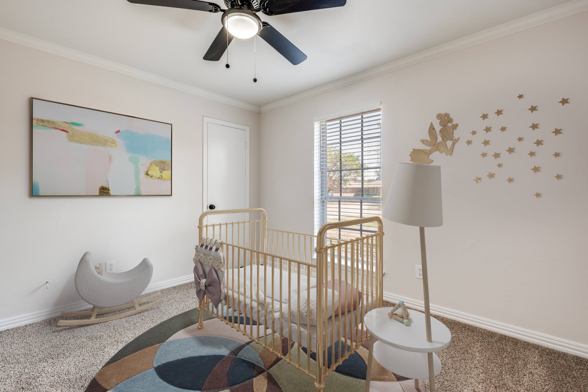 Virtually staged nursery with gold crib, moon rocker, colorful rug, wall art, and fairy decals in Mesquite, Texas